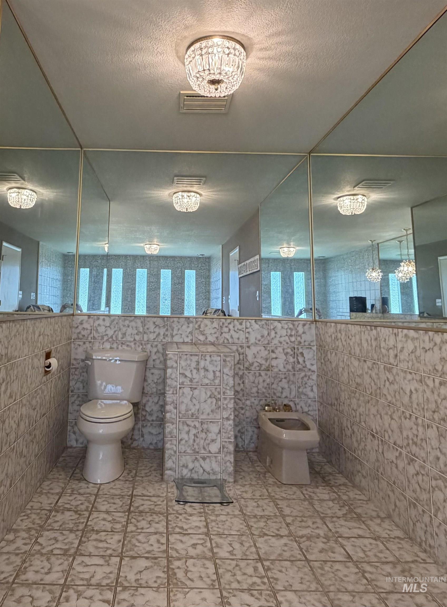 Bathroom featuring full wall tiling and mirrored wall panels