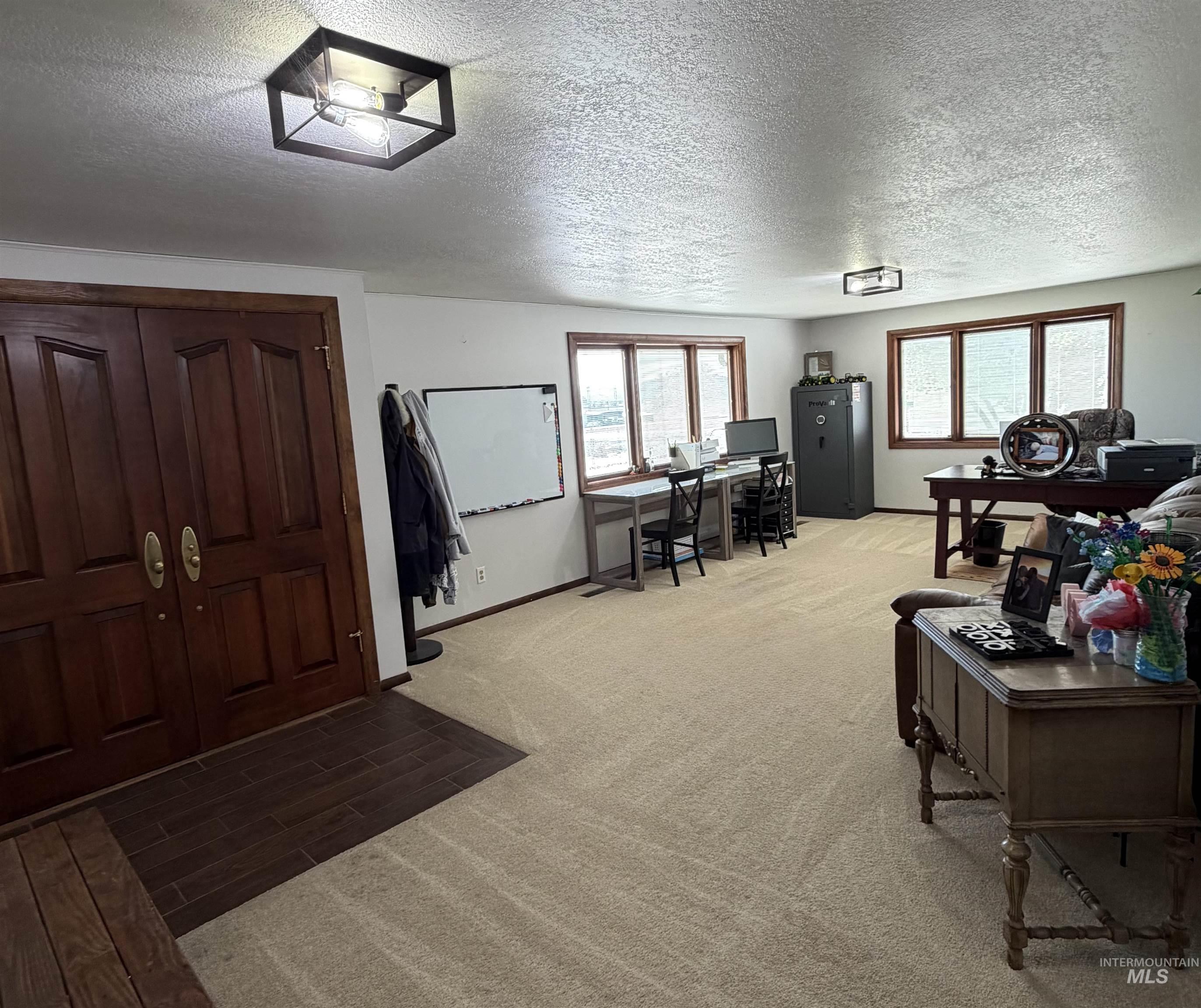Spacious room featuring light-toned carpeting and multiple windows with wood trim