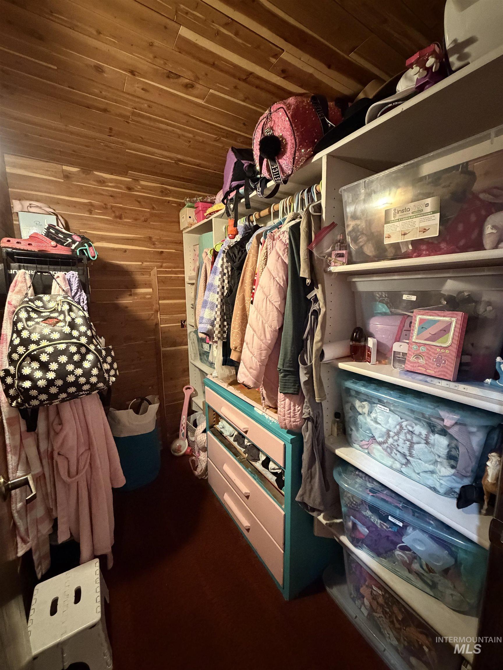 Custom closet space featuring cedar plank walls and ceiling, built-in shelving, hanging rods, and an integrated drawer unit