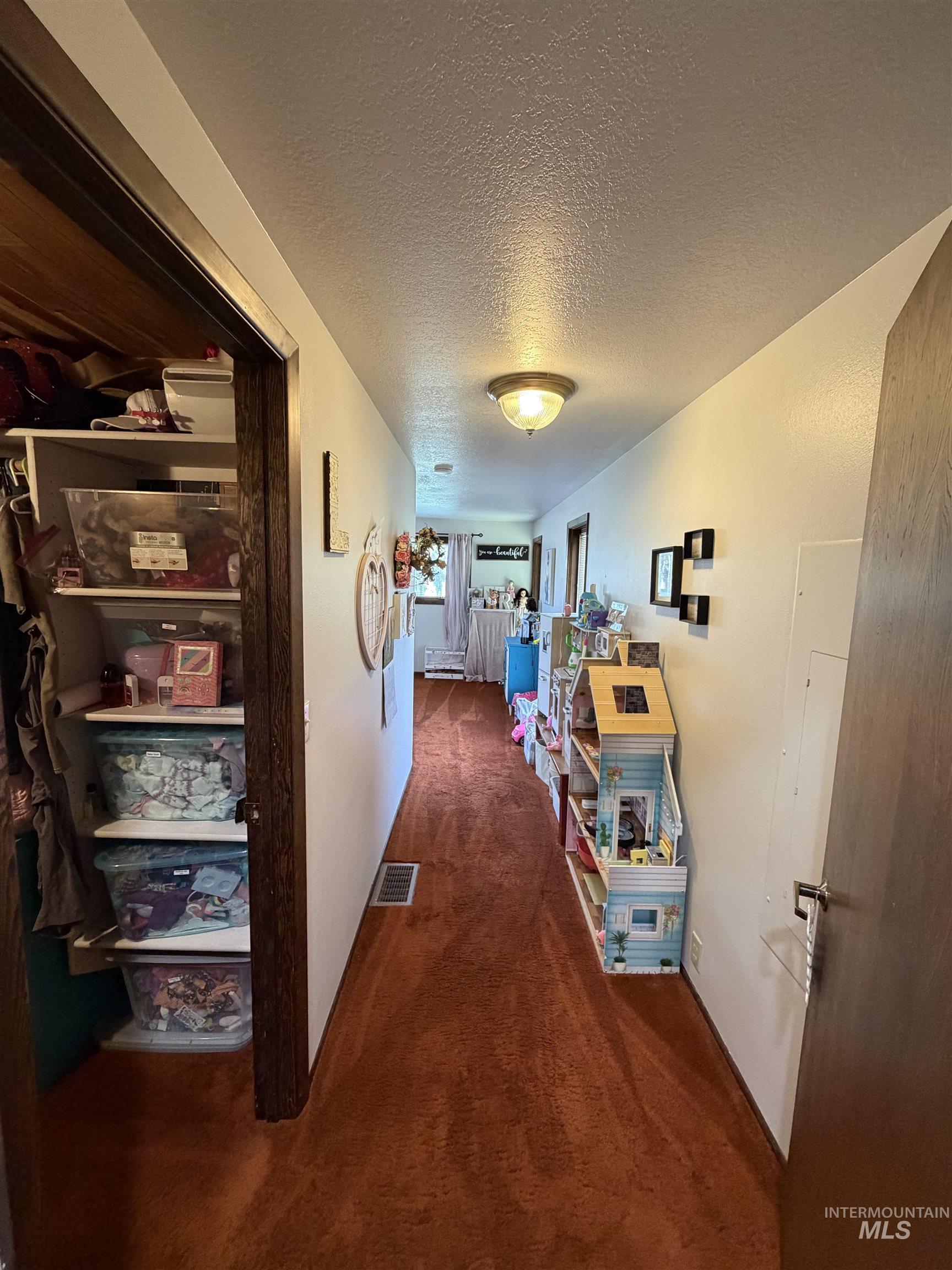 Hallway featuring rich-toned carpeting, white walls, and a flush-mount ceiling light fixture