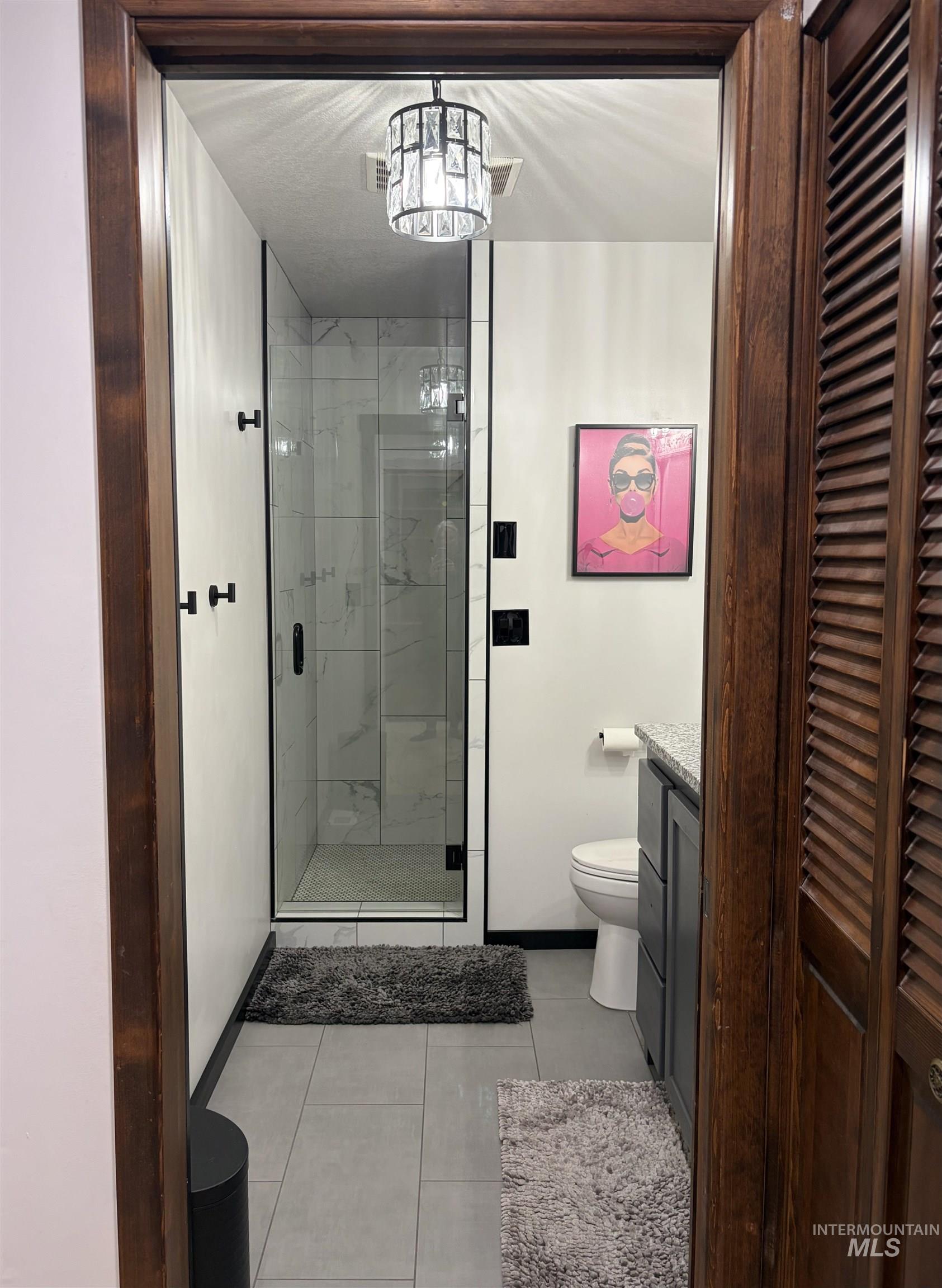 Framed entrance to a bathroom featuring a walk-in shower with clear glass enclosure and black trim, complemented by white subway tile walls