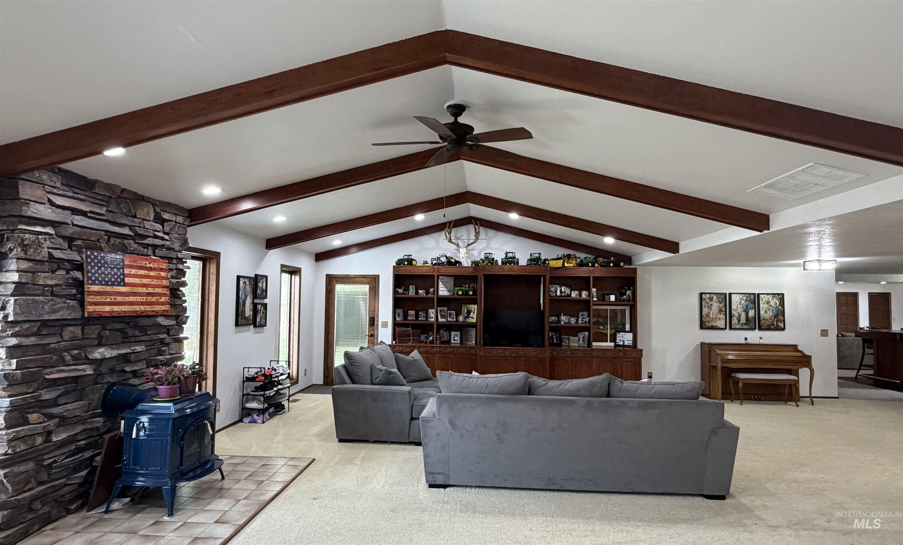 Living area featuring a vaulted ceiling with exposed wood beams, recessed lighting, and a ceiling fan