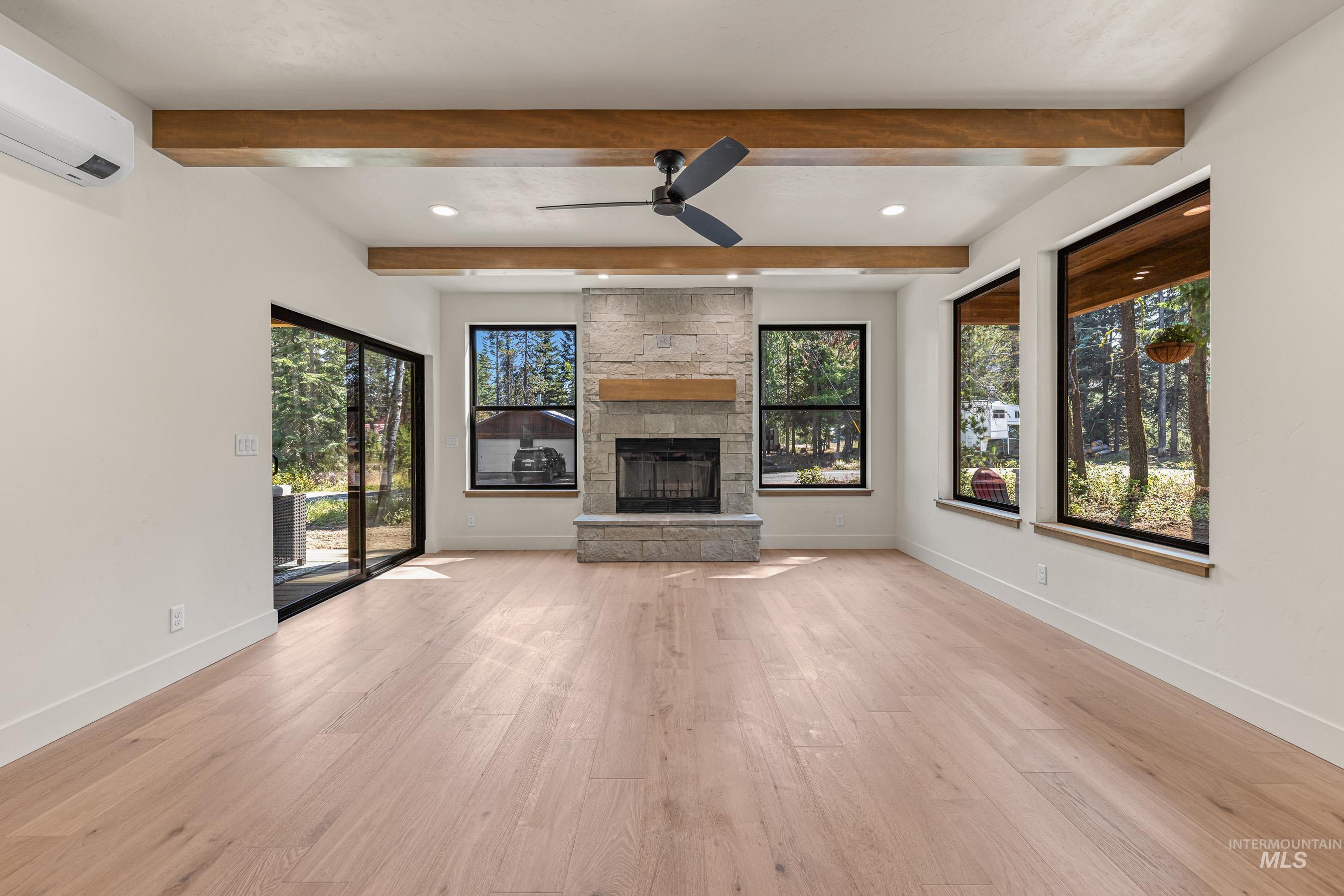 Unfurnished living room featuring light wood-type flooring, a fireplace, ceiling fan, recessed lighting, and plenty of natural light