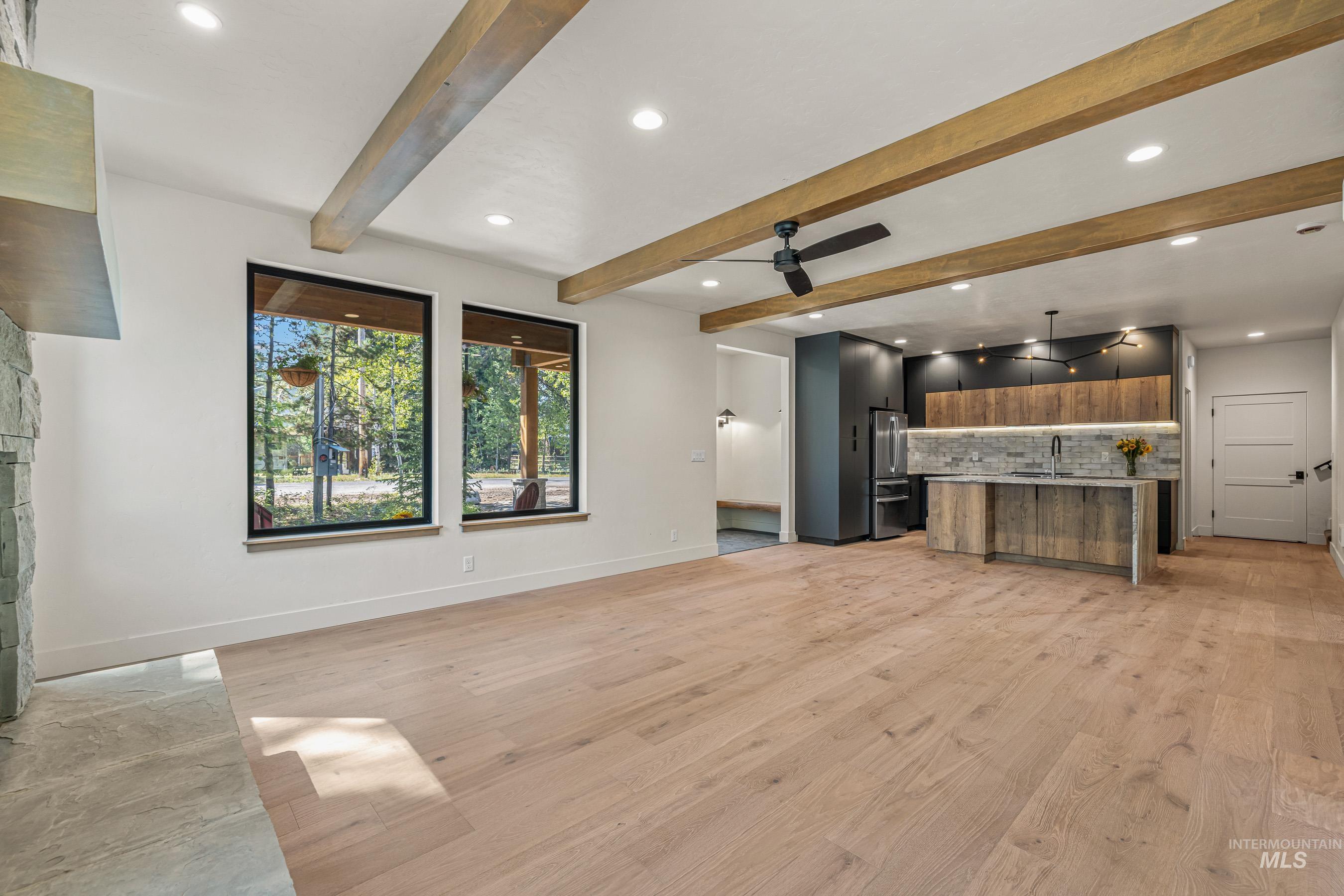 Unfurnished living room with recessed lighting, light wood-style flooring, beam ceiling, and ceiling fan