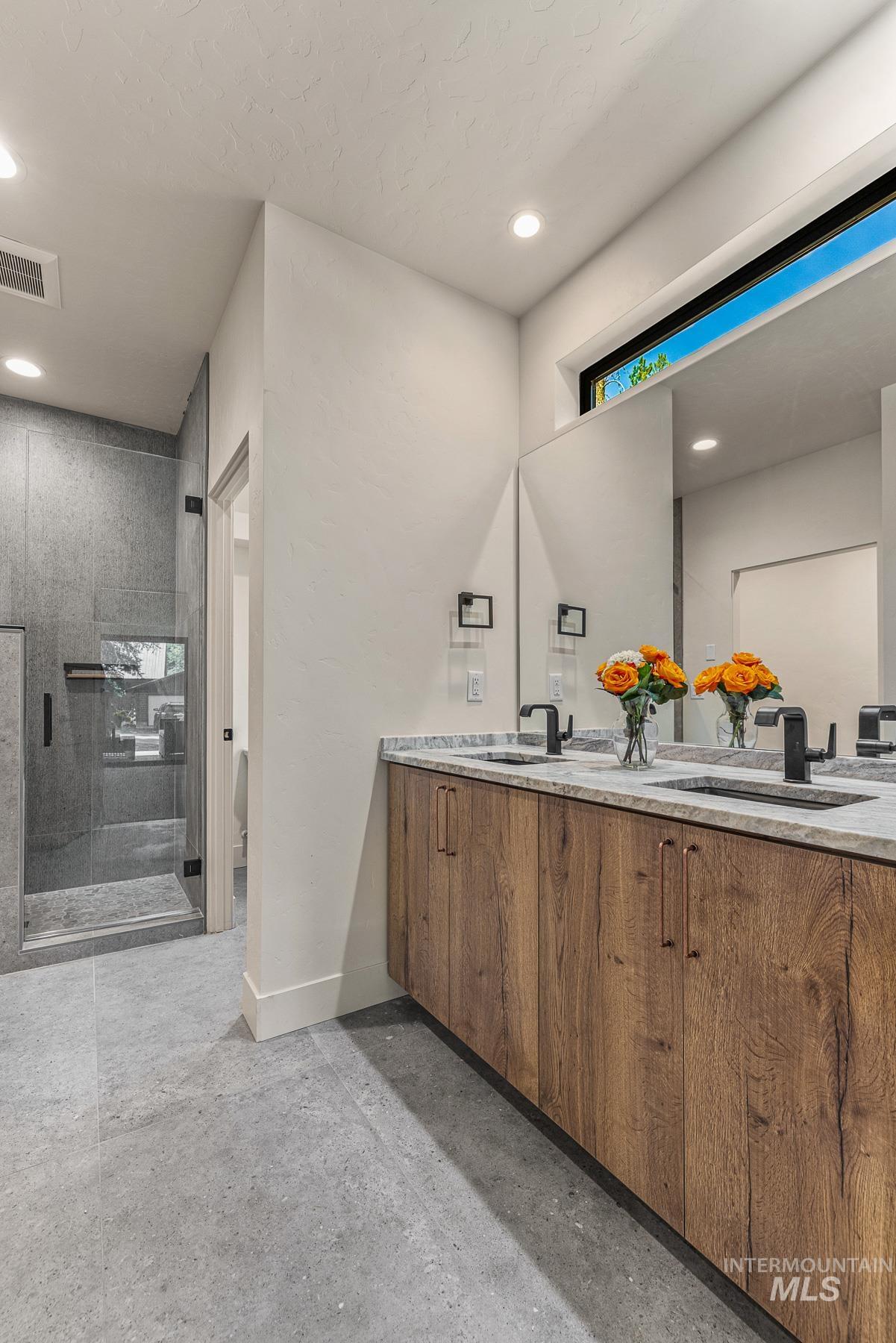 Bathroom featuring double vanity, a stall shower, and recessed lighting