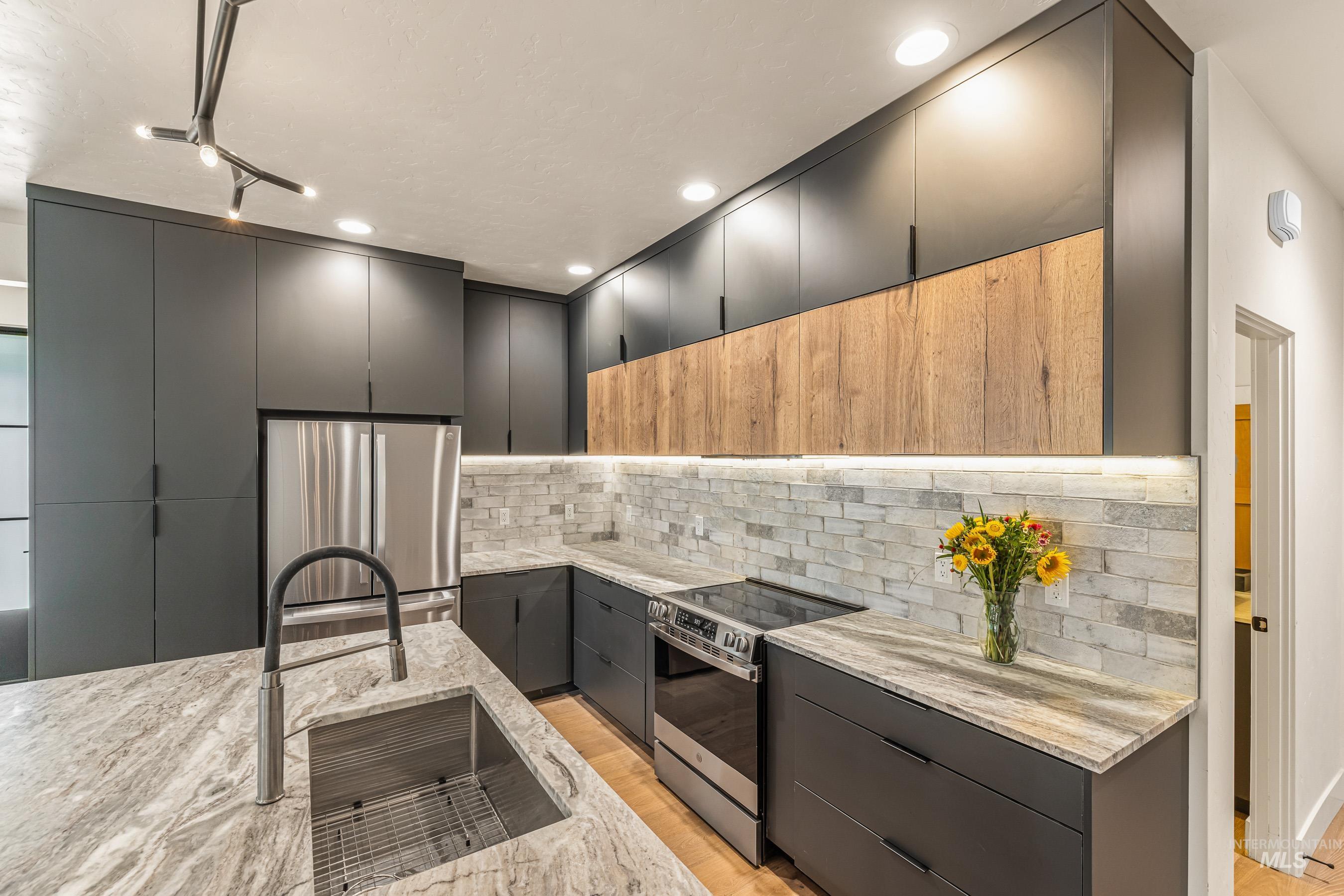 Kitchen featuring stainless steel appliances, light stone countertops, modern cabinets, recessed lighting, and two tone color scheme