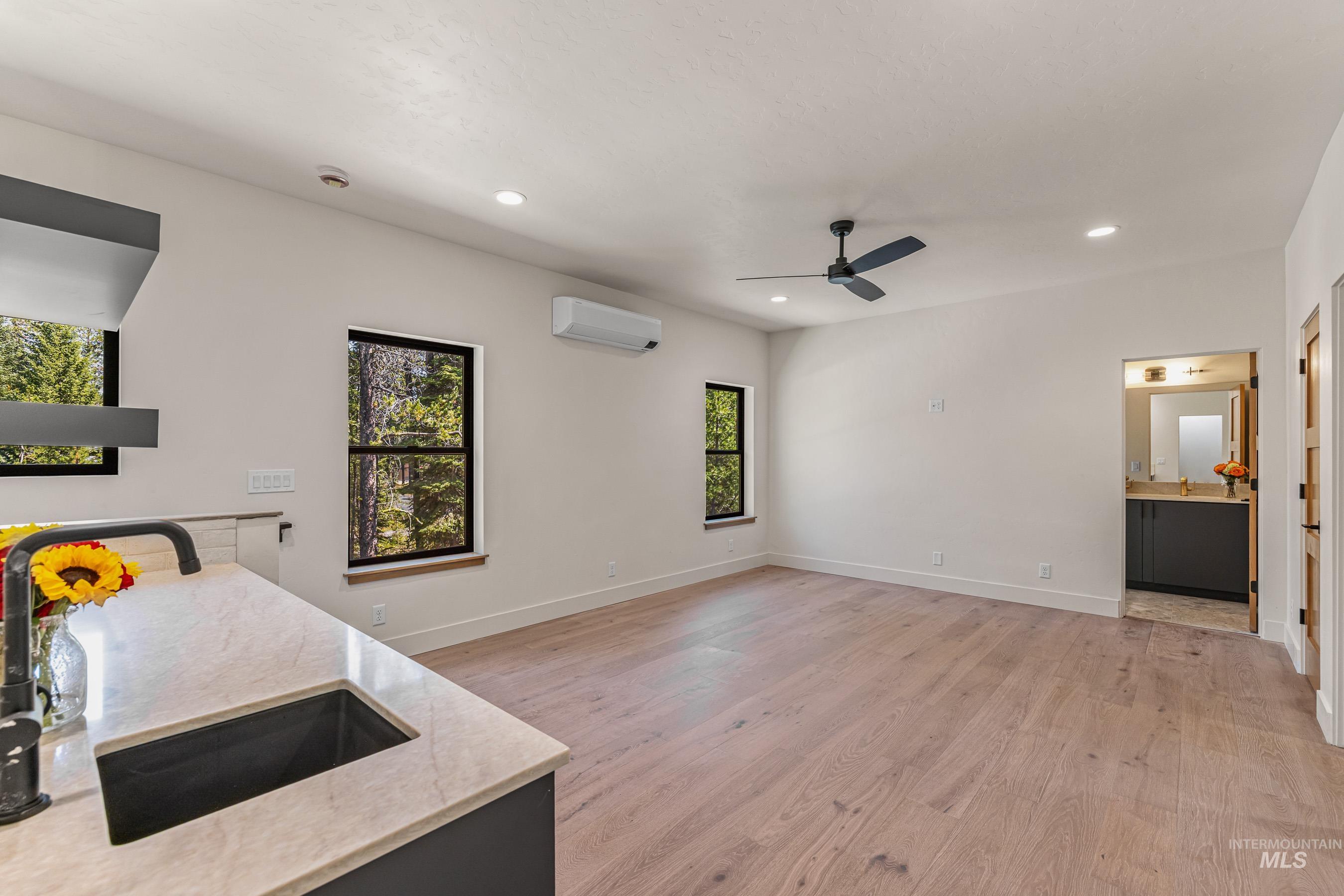 Kitchen featuring light wood-style flooring, light stone countertops, ceiling fan, recessed lighting, and open floor plan