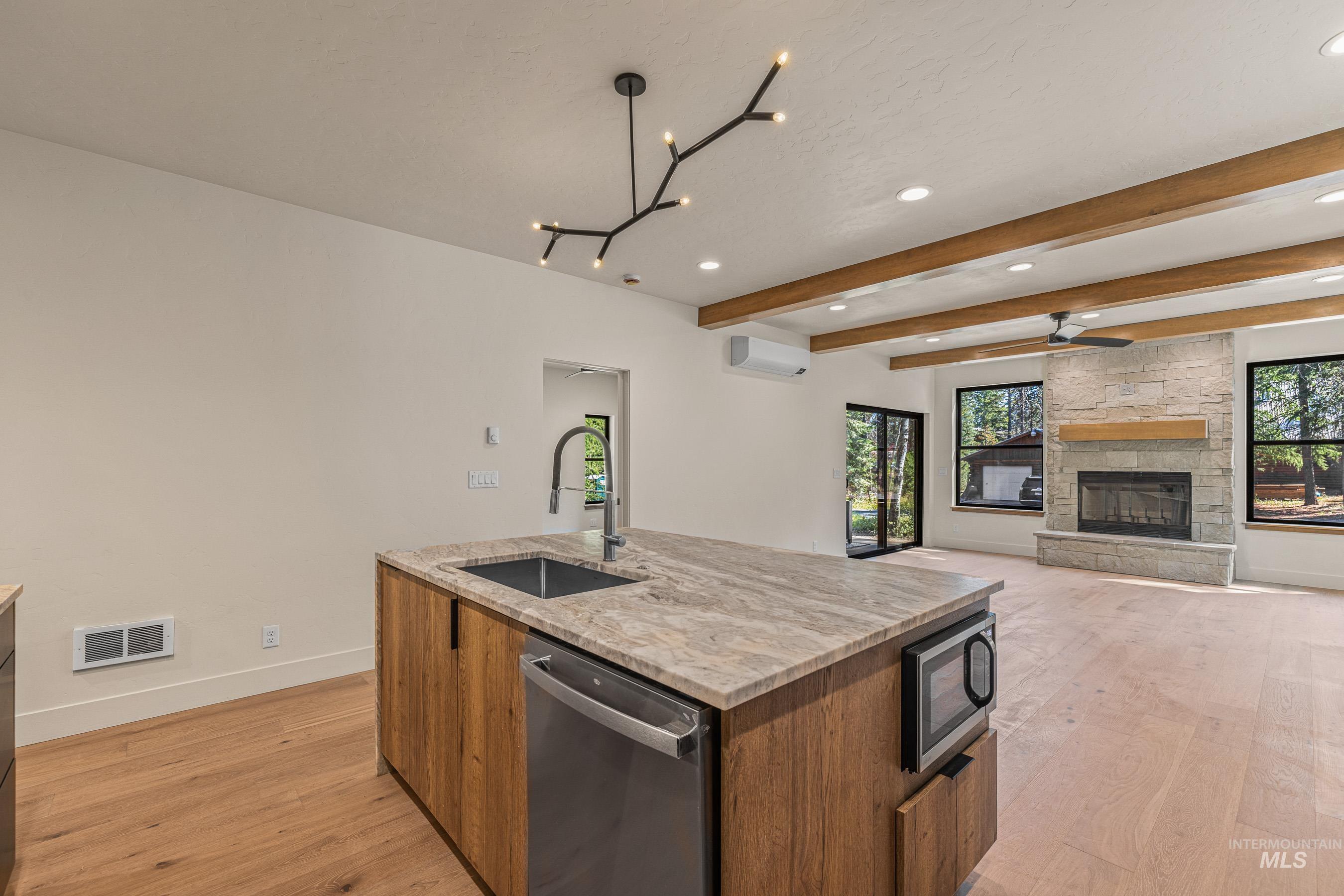 Kitchen with light stone countertops, wood finish cabinetry, modern cabinets, stainless steel appliances, and an island with sink
