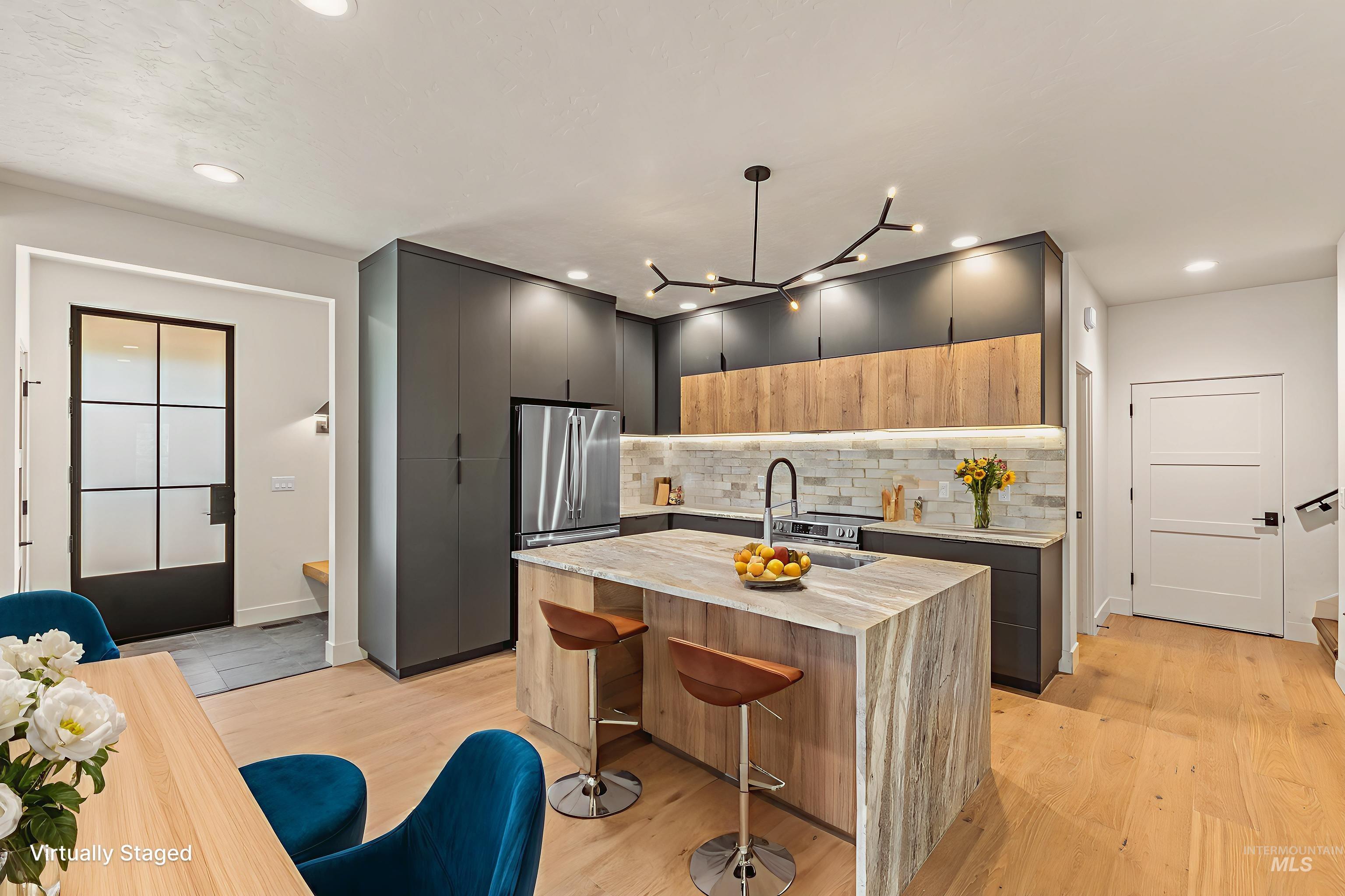 Kitchen with two tone color scheme, light stone countertops, modern cabinets, a breakfast bar area, and light wood-type flooring