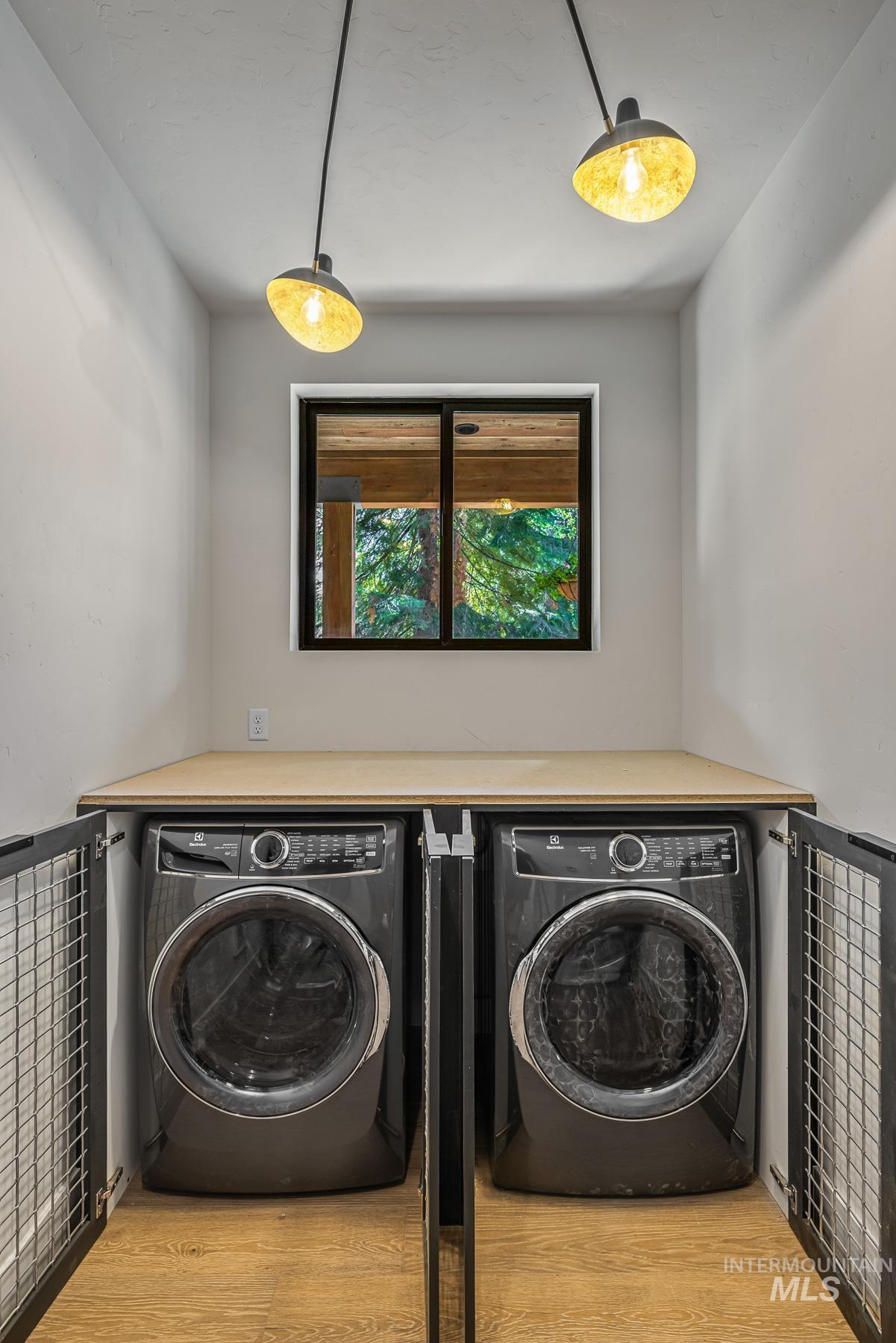 Laundry area with independent washer and dryer and light wood-type flooring