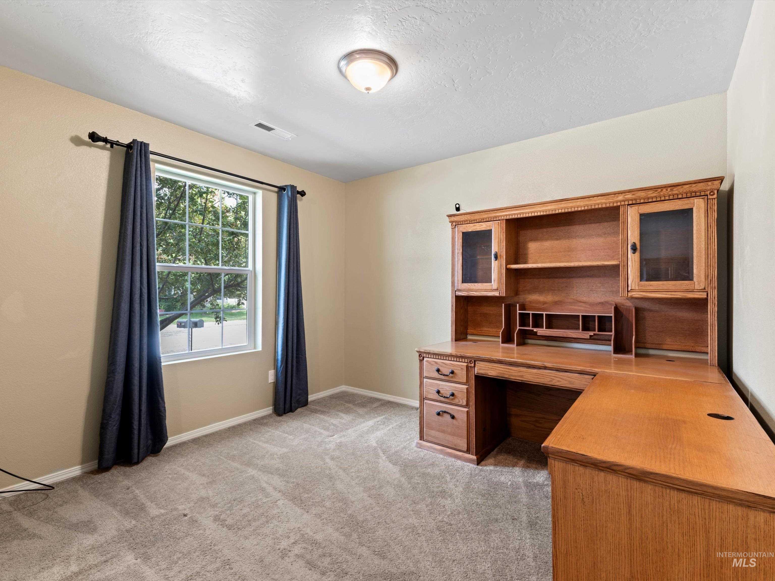 Home office featuring light carpet and a textured ceiling