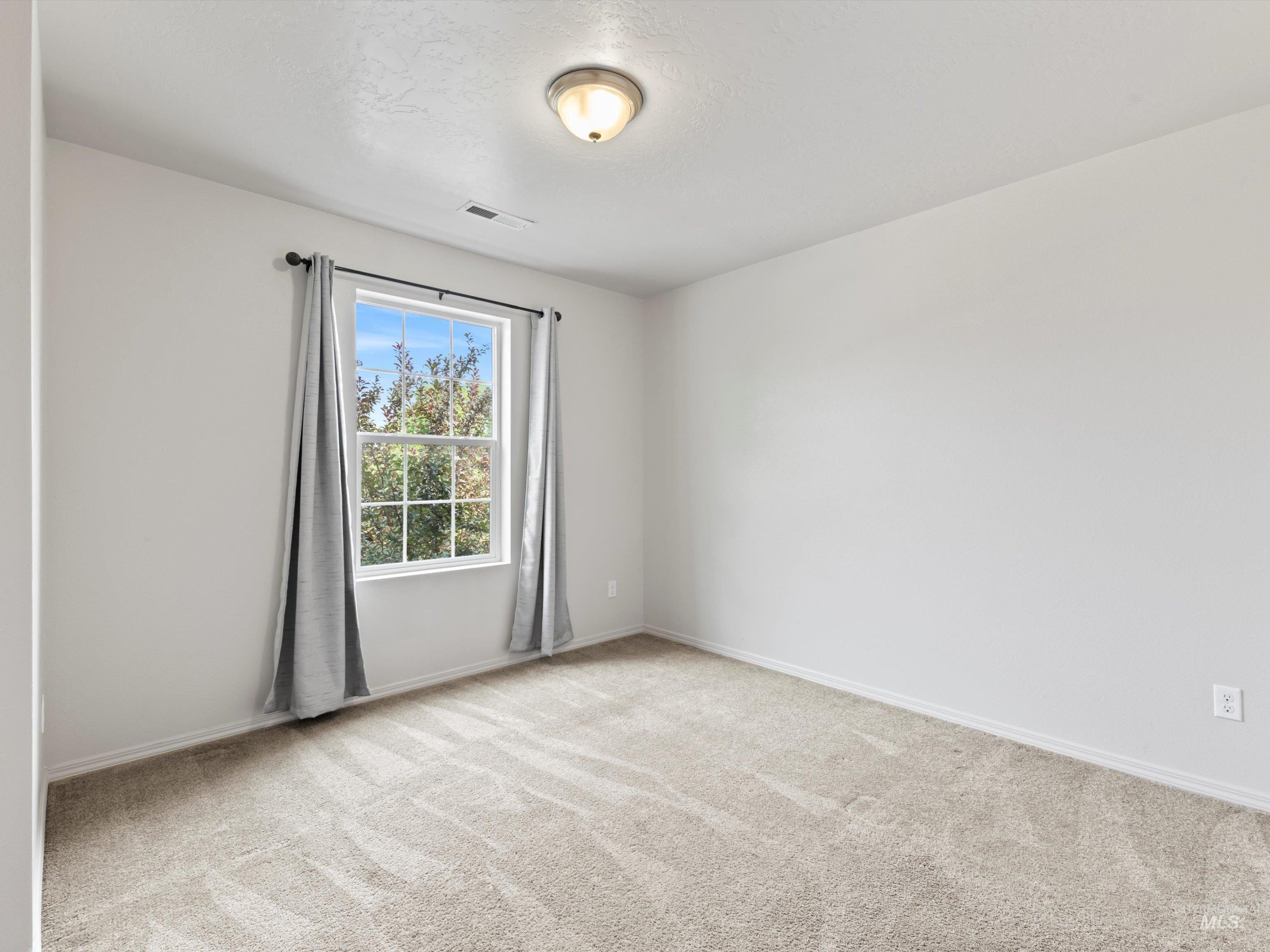 Empty room featuring light carpet and baseboards