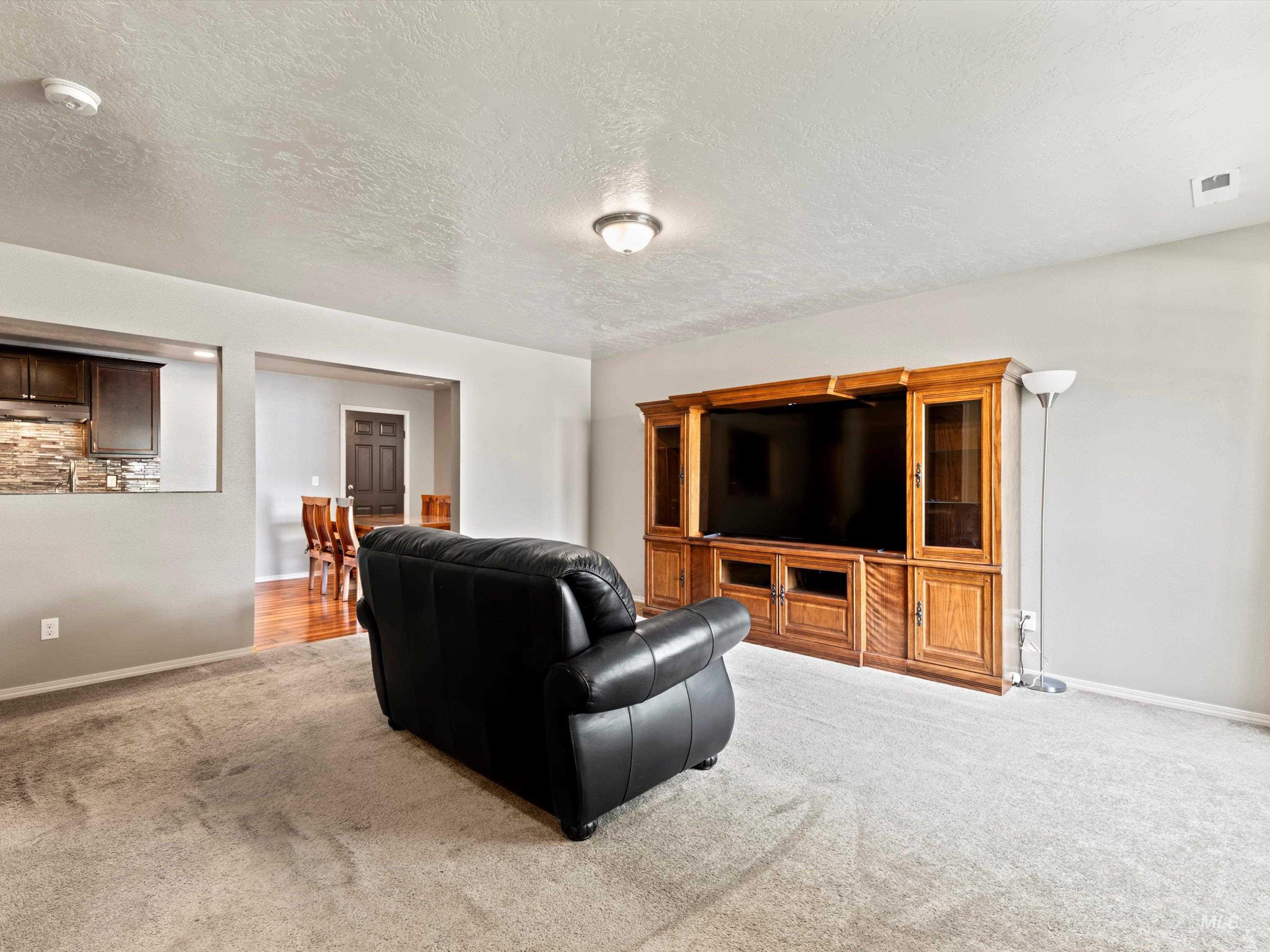Living area with light colored carpet and a textured ceiling