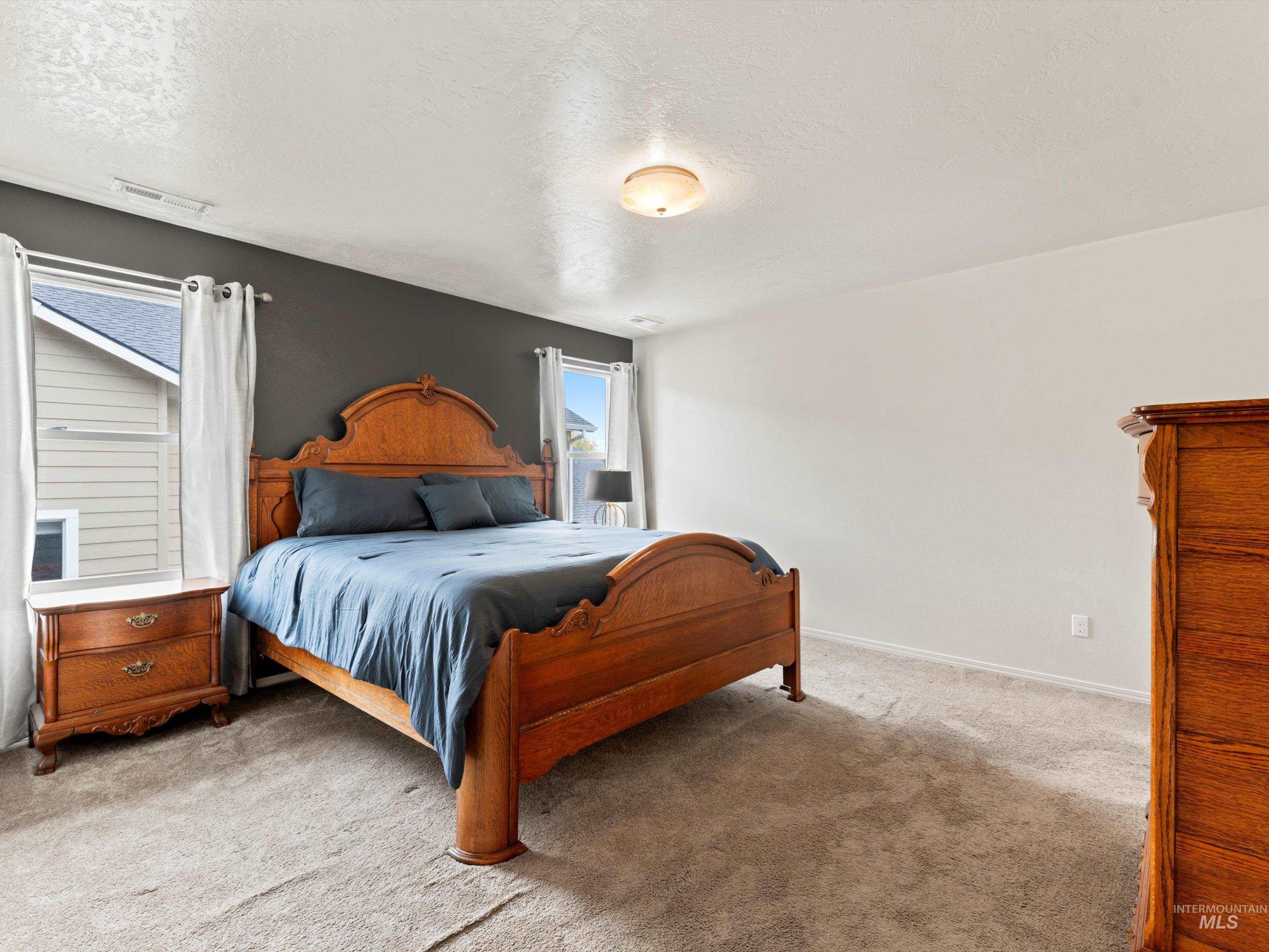 Carpeted bedroom featuring a textured ceiling and baseboards
