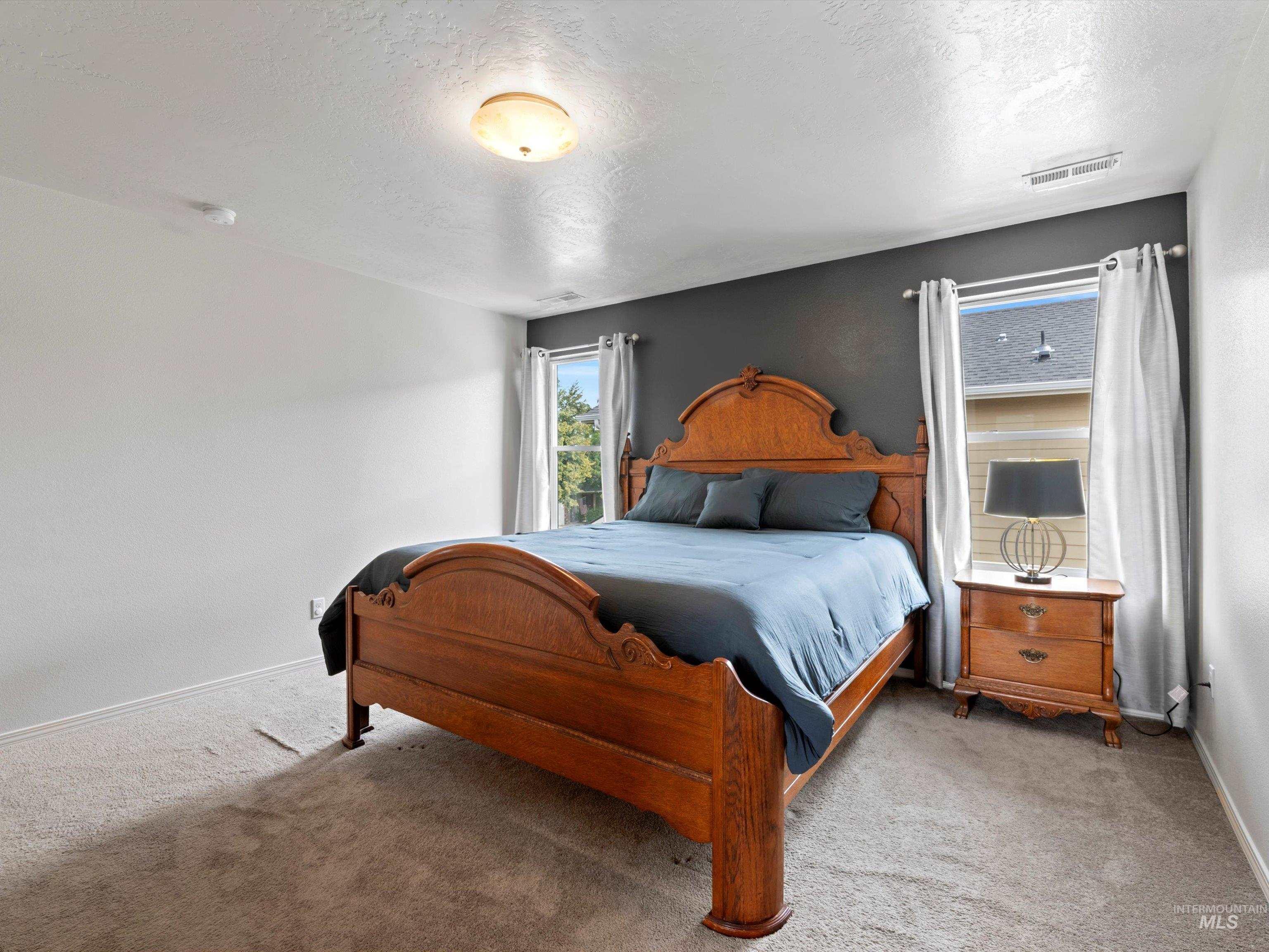 Carpeted bedroom with a textured ceiling and baseboards