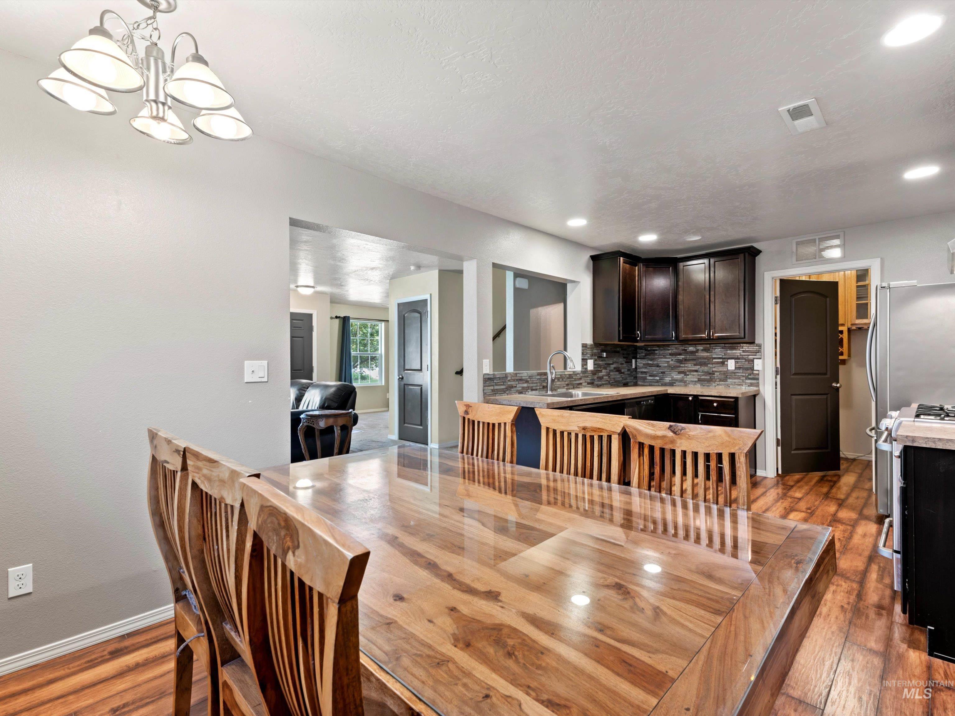 Dining room featuring dark wood-style flooring, a chandelier, and recessed lighting