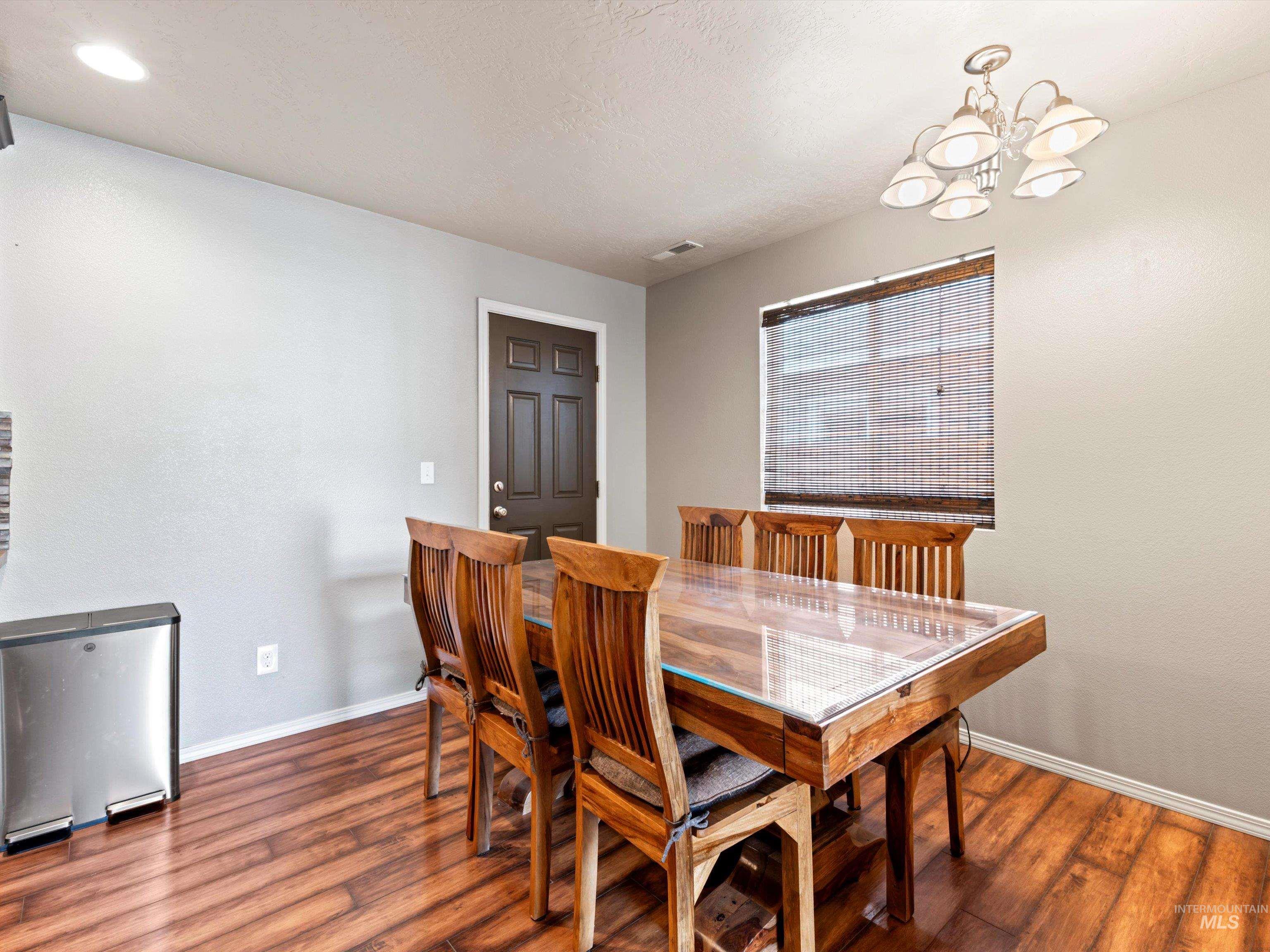 Dining space featuring wood finished floors, a chandelier, and a textured ceiling