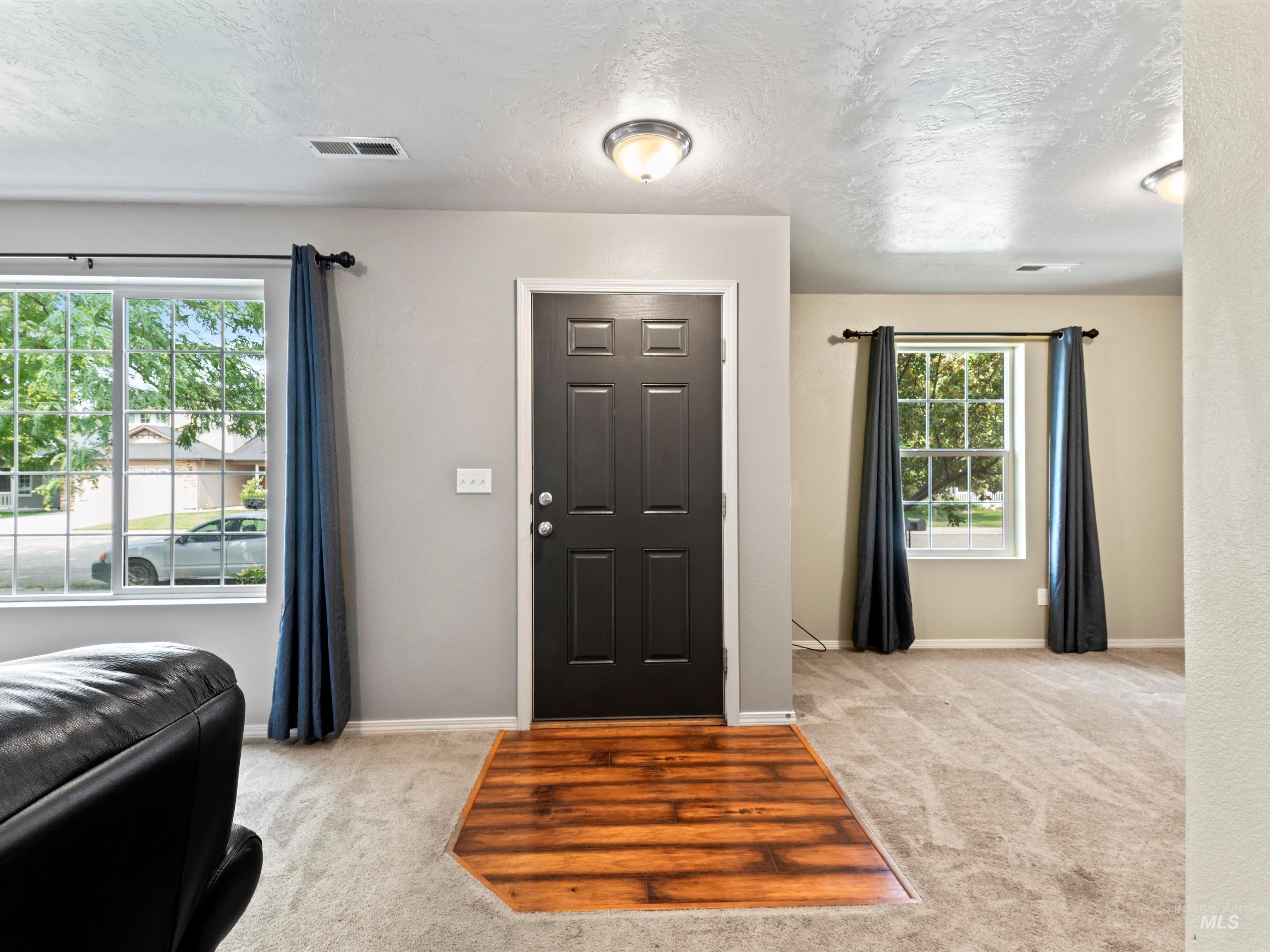 Entryway with light carpet and a textured ceiling