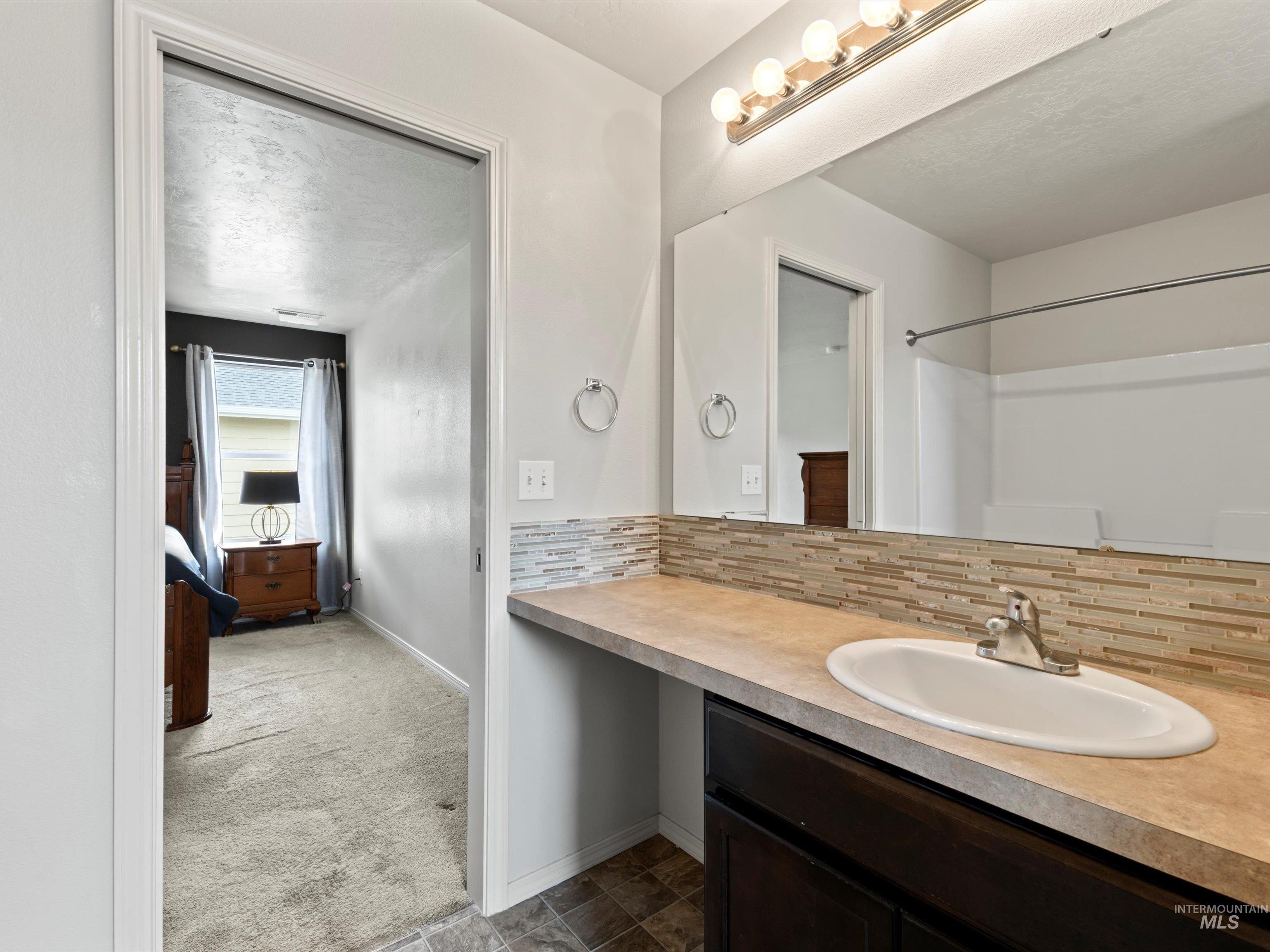 Bathroom featuring decorative backsplash and vanity