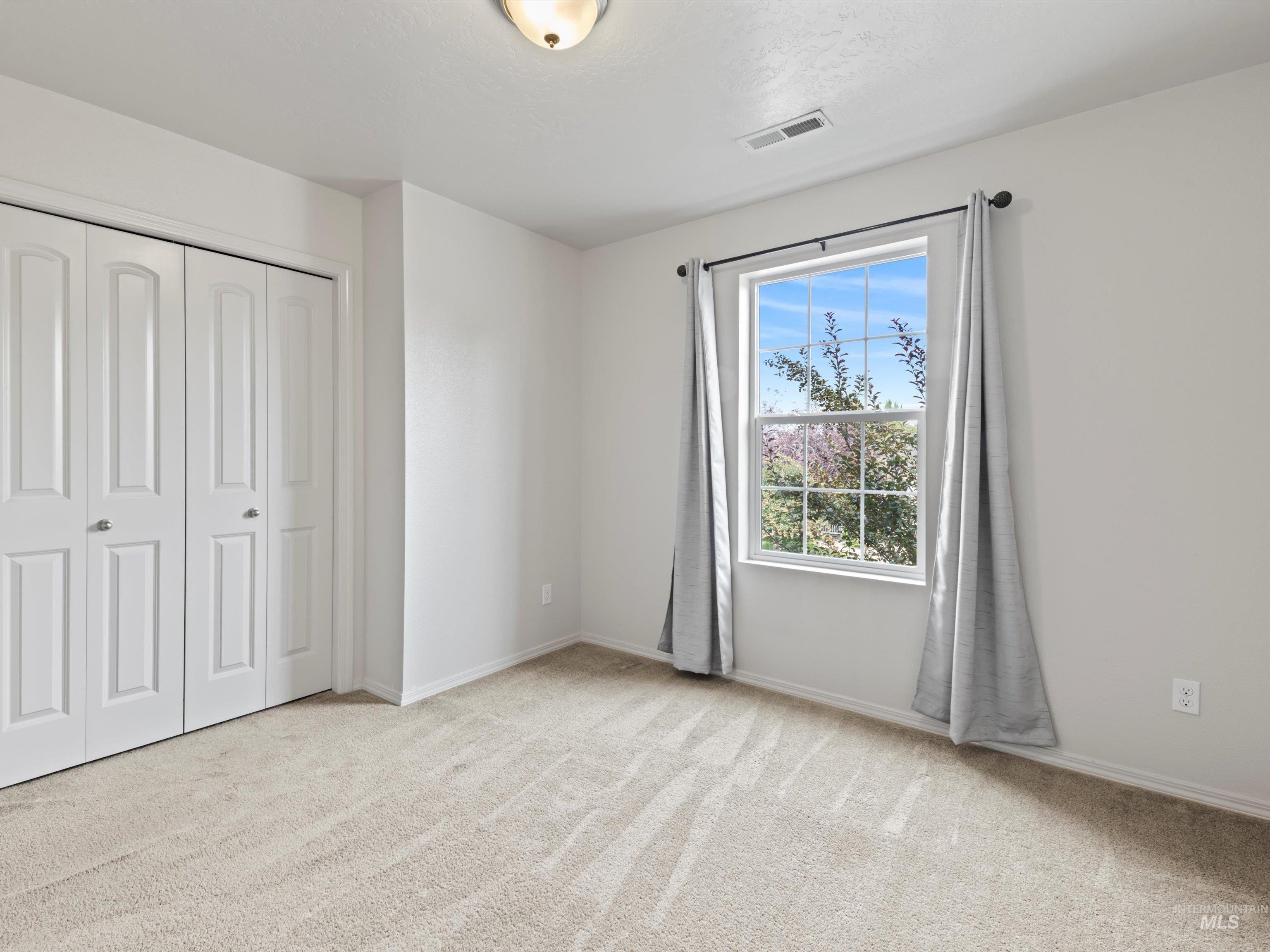 Unfurnished bedroom with light colored carpet and a closet