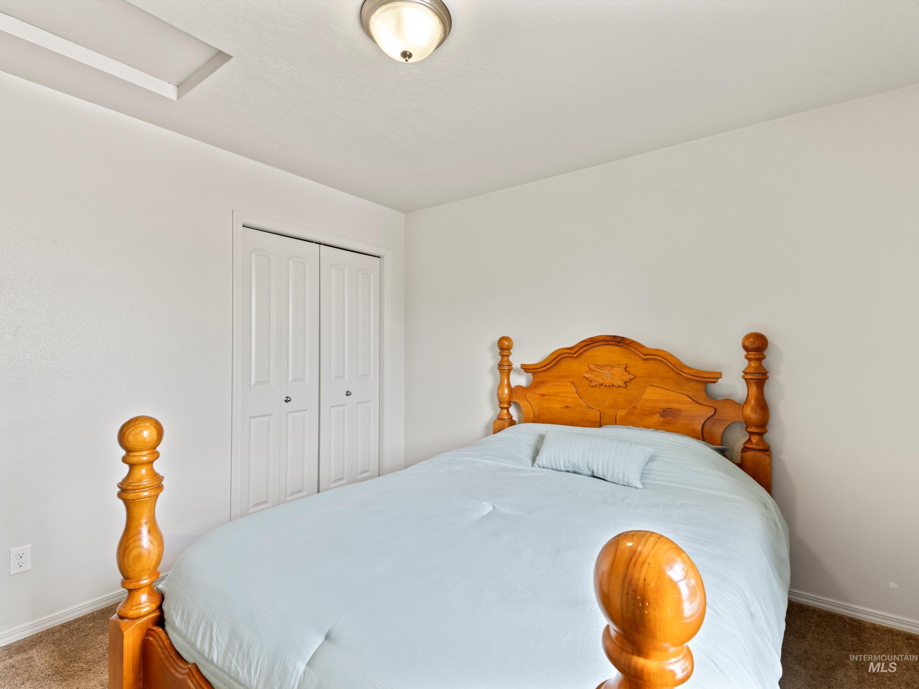 Carpeted bedroom featuring a closet and attic access