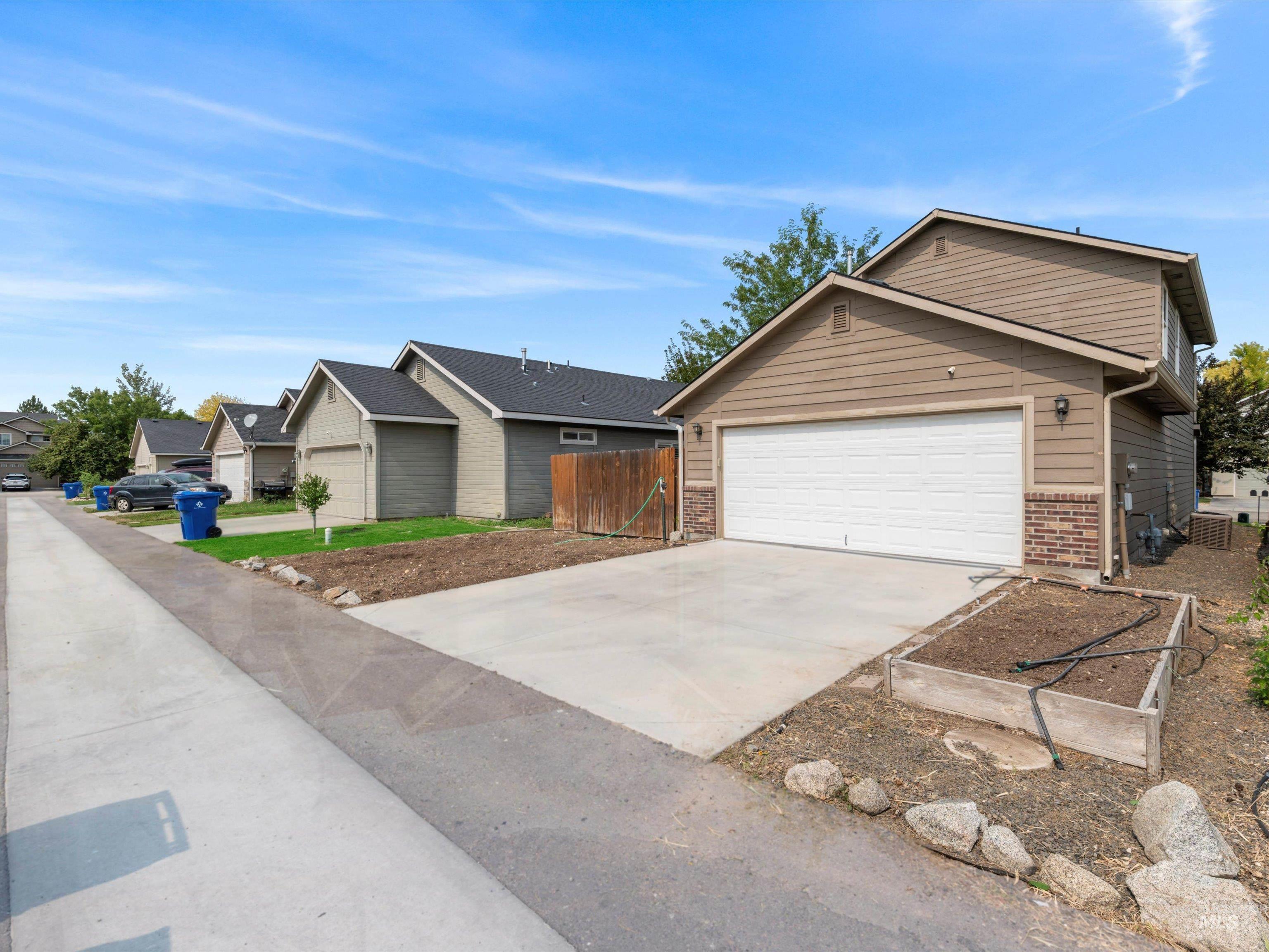 Ranch-style home featuring concrete driveway, brick siding, a residential view, and a garage