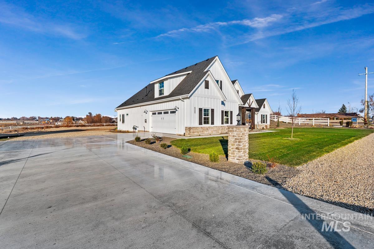 View of side of property with board and batten siding, driveway, roof with shingles, stone siding, and a garage