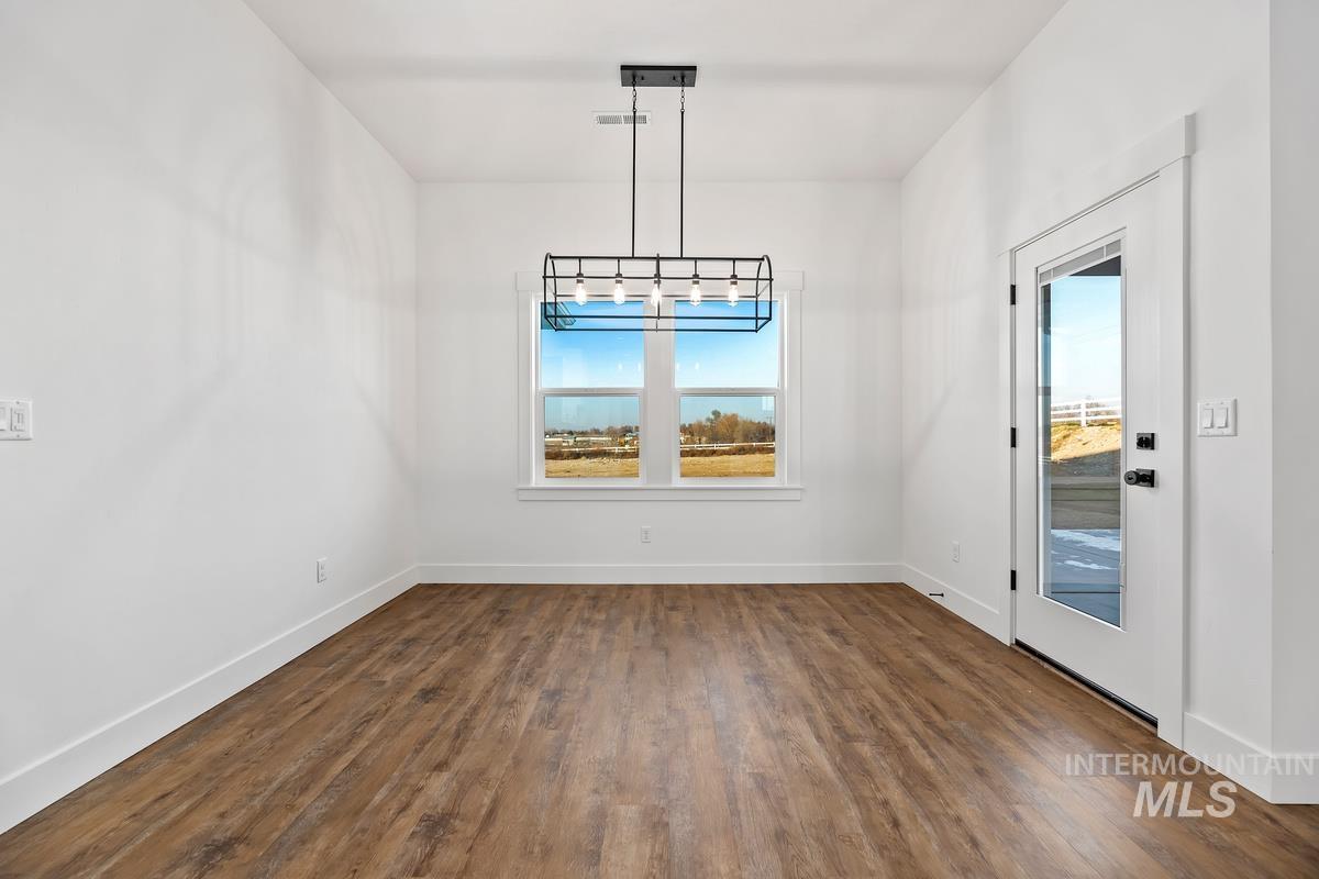 Unfurnished dining area with dark wood-style floors and baseboards