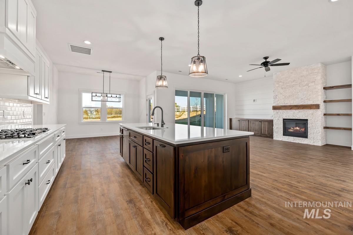 Kitchen with white cabinets, dark brown cabinets, hanging light fixtures, dark wood finished floors, and open floor plan