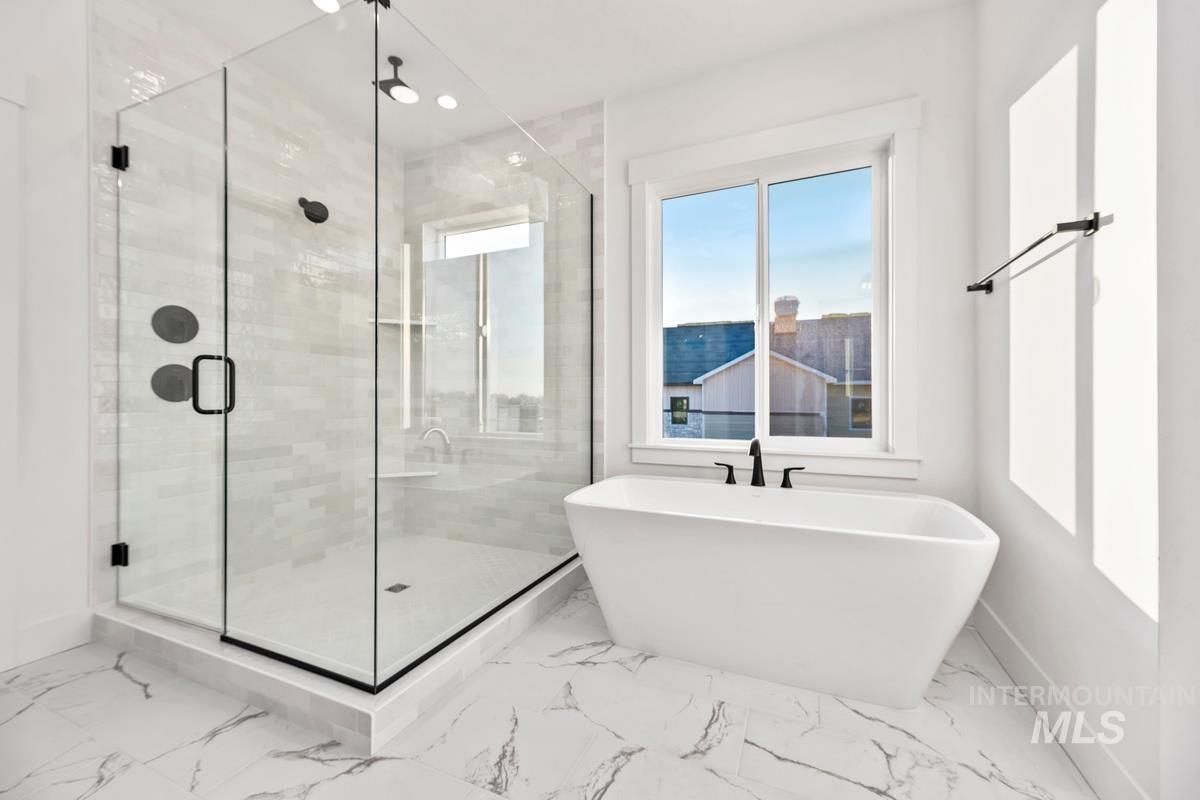 Bathroom featuring a stall shower, a soaking tub, and marble finish flooring