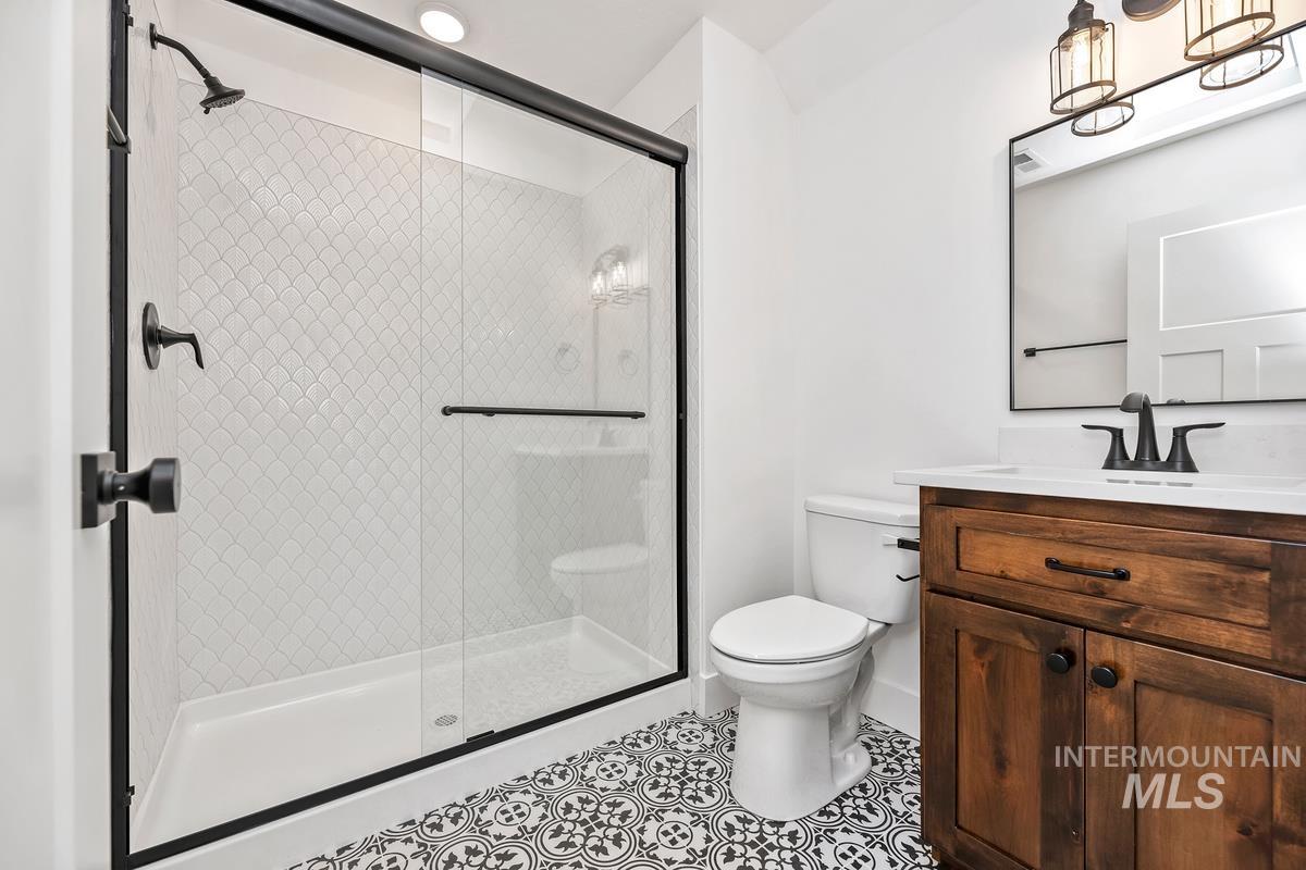 Full bath featuring vanity, a shower stall, and tile patterned flooring