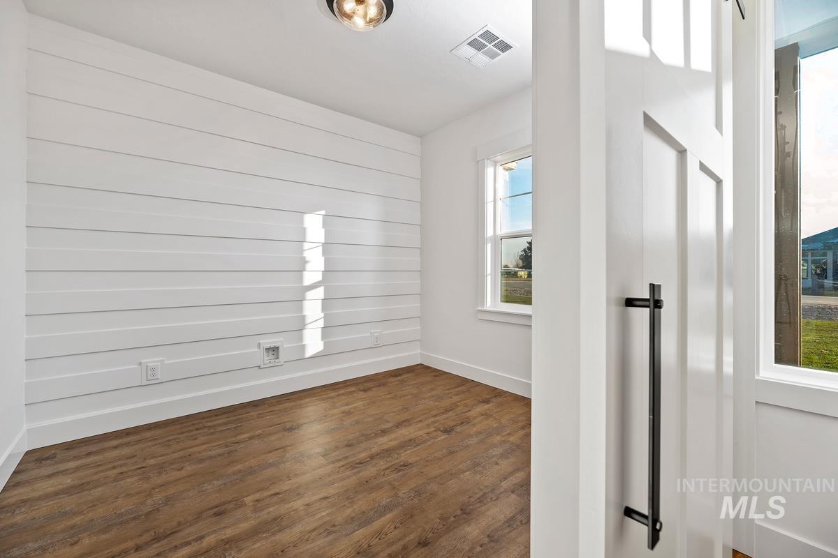 Spare room with dark wood-style flooring and baseboards