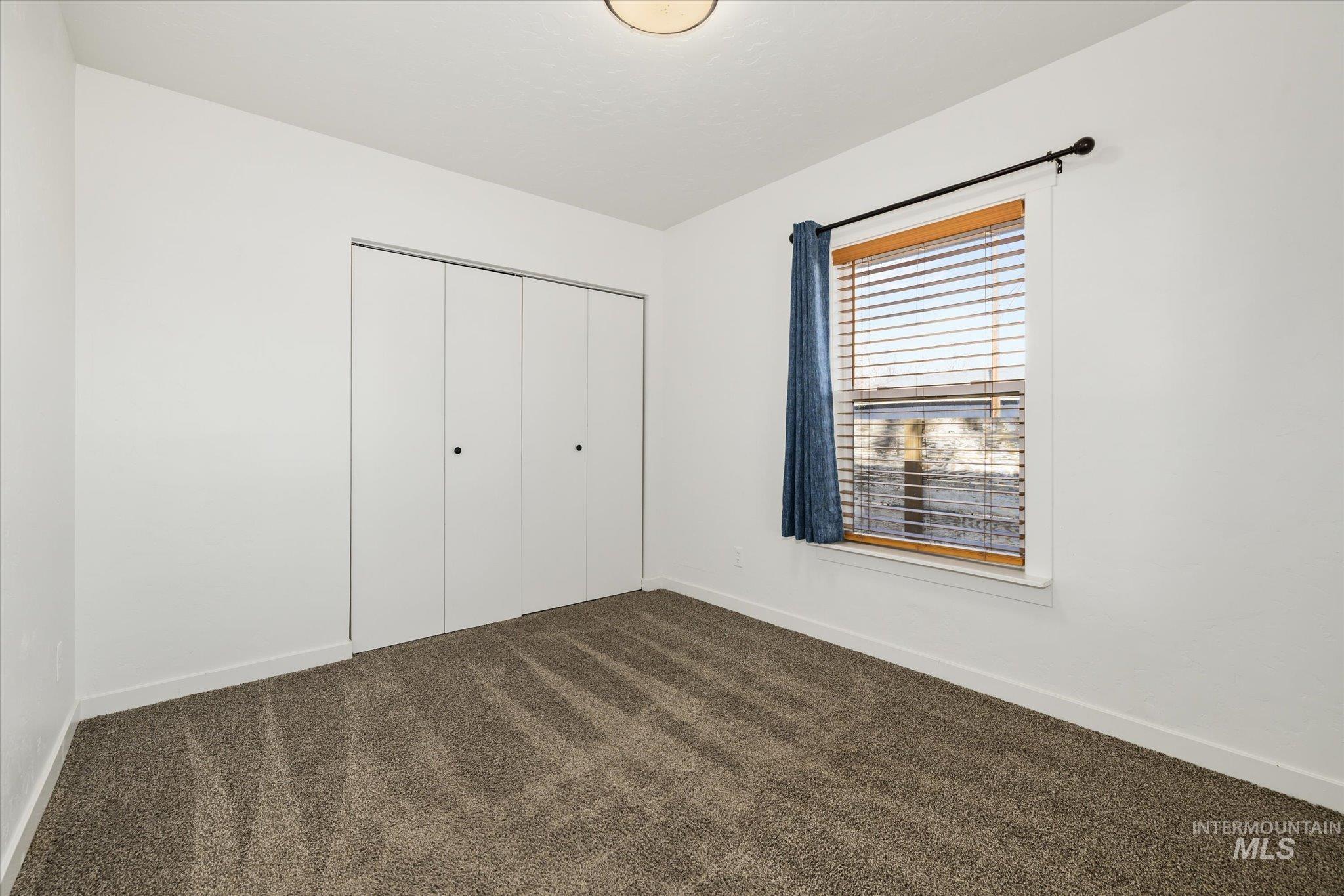 Unfurnished bedroom featuring dark carpet and a closet