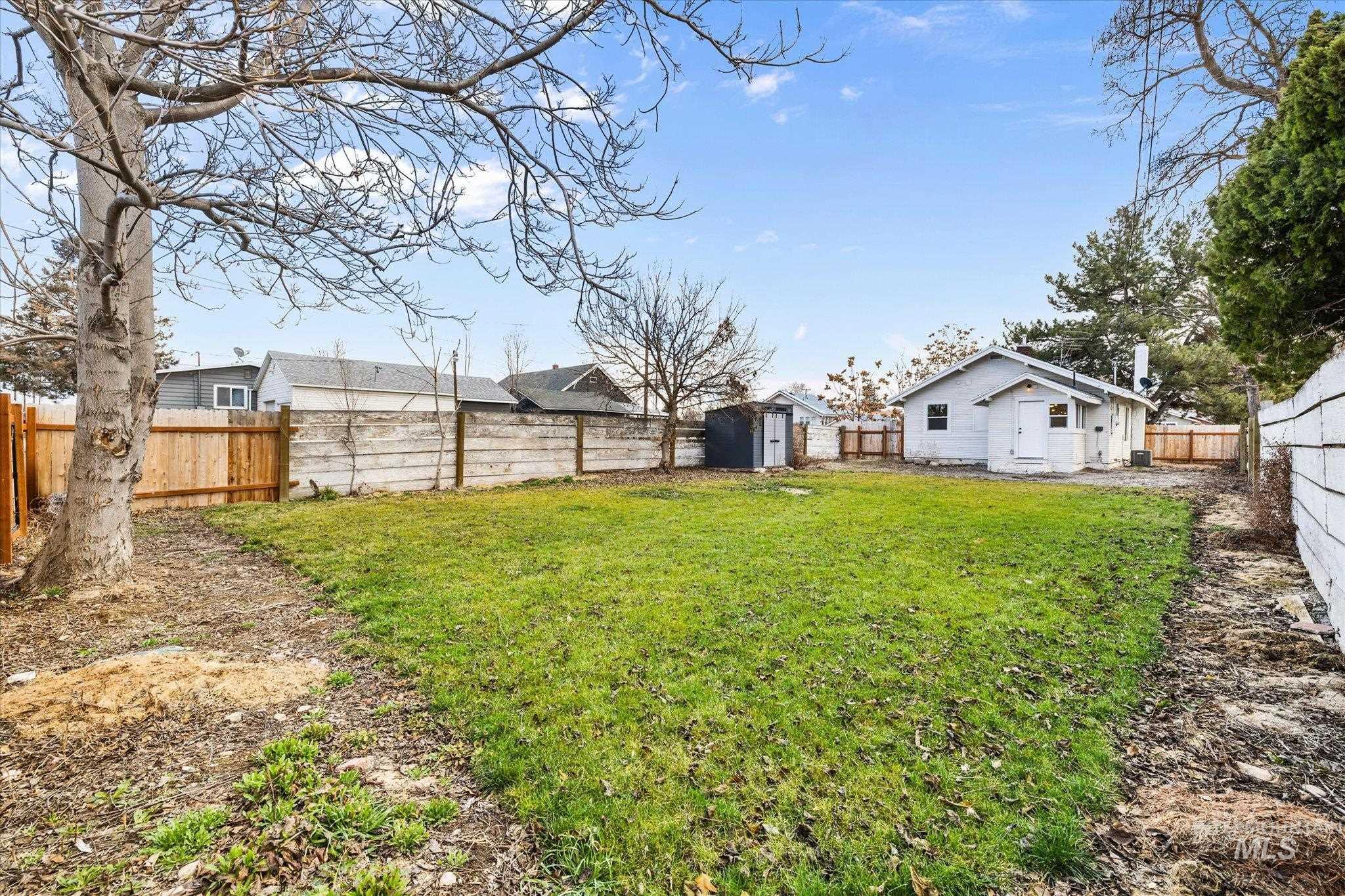 Fenced backyard featuring a storage shed