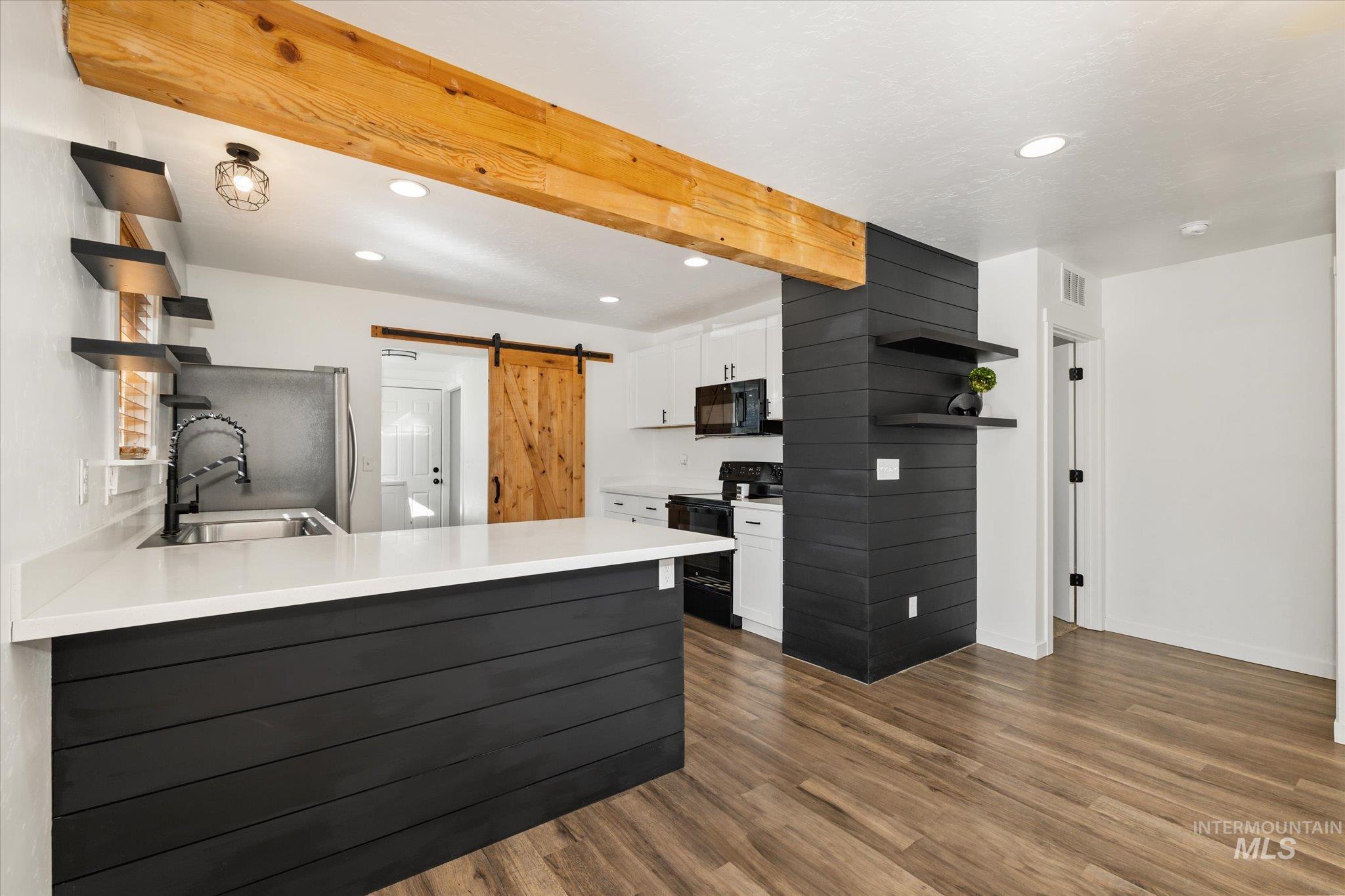 Kitchen featuring open shelves, a barn door, white cabinetry, black appliances, and recessed lighting