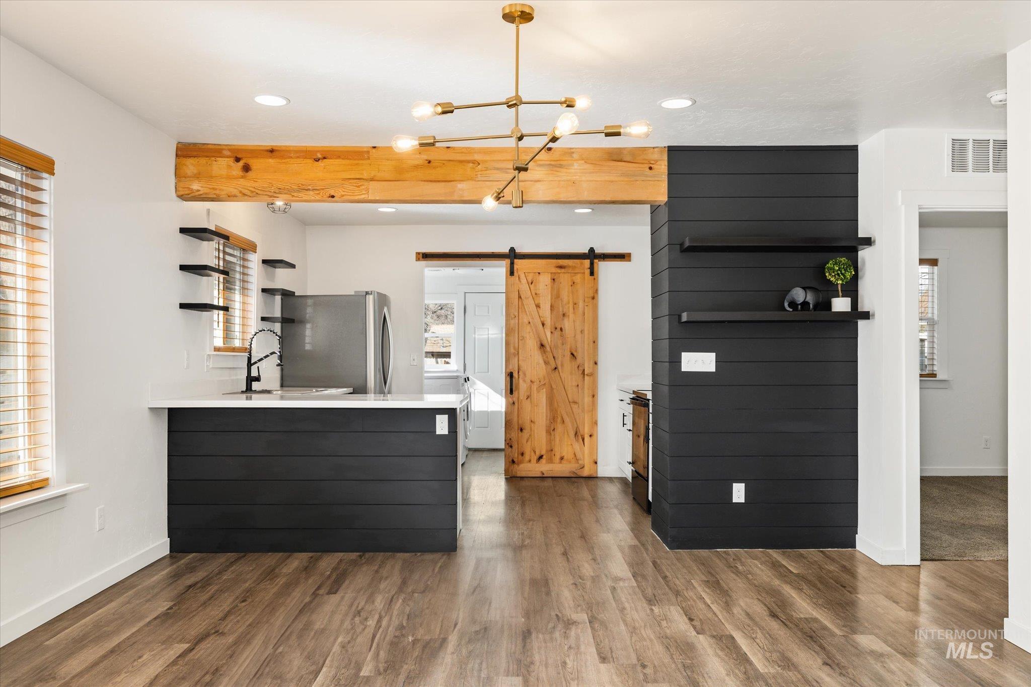 Kitchen with a barn door, light countertops, open shelves, and freestanding refrigerator