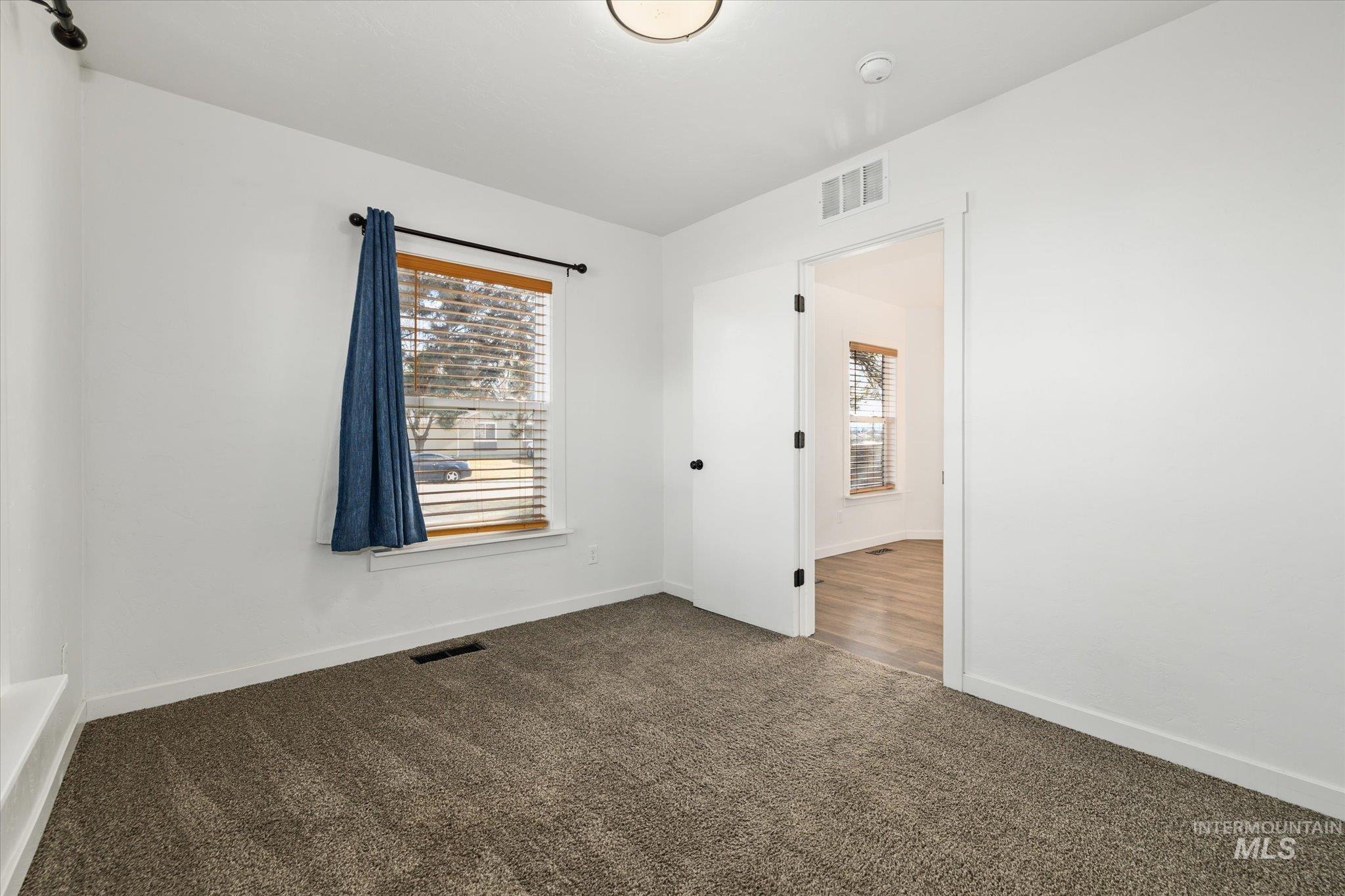 Empty room featuring dark carpet and baseboards