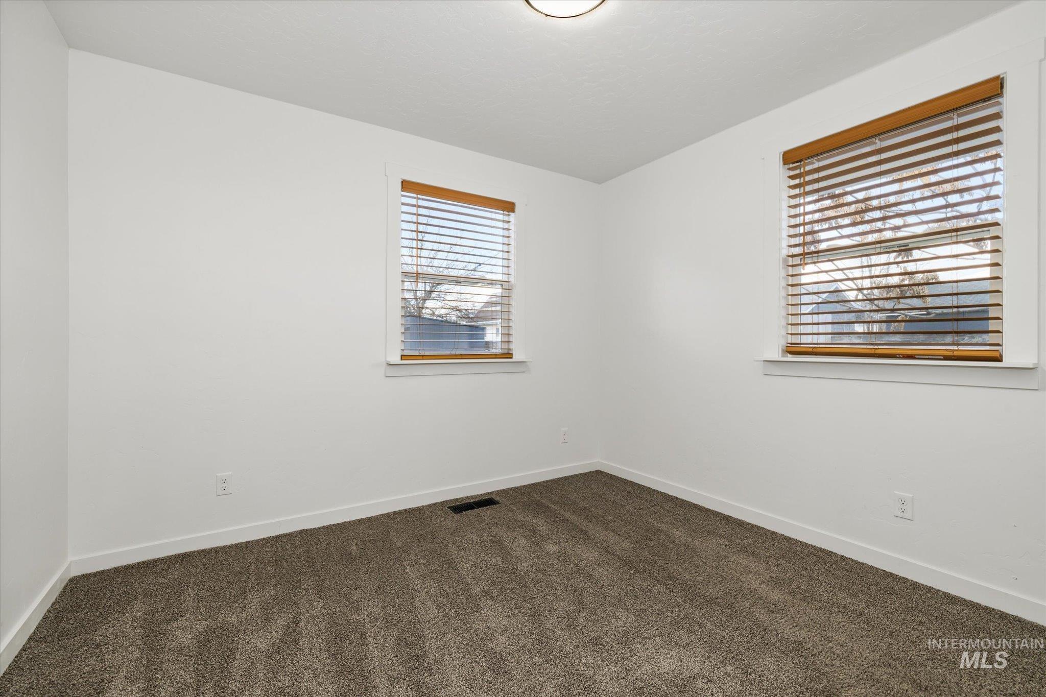 Spare room with dark carpet and baseboards