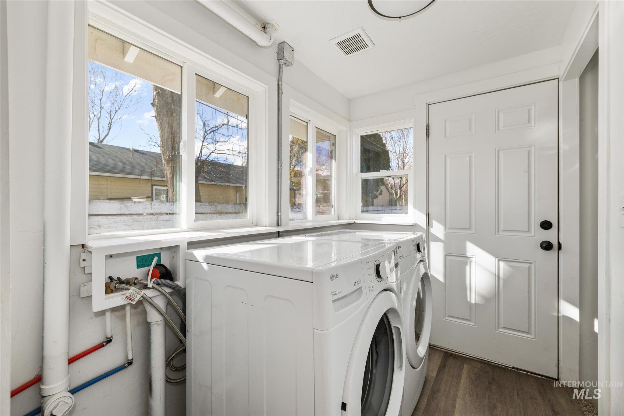 Laundry area with dark wood finished floors and washing machine and clothes dryer