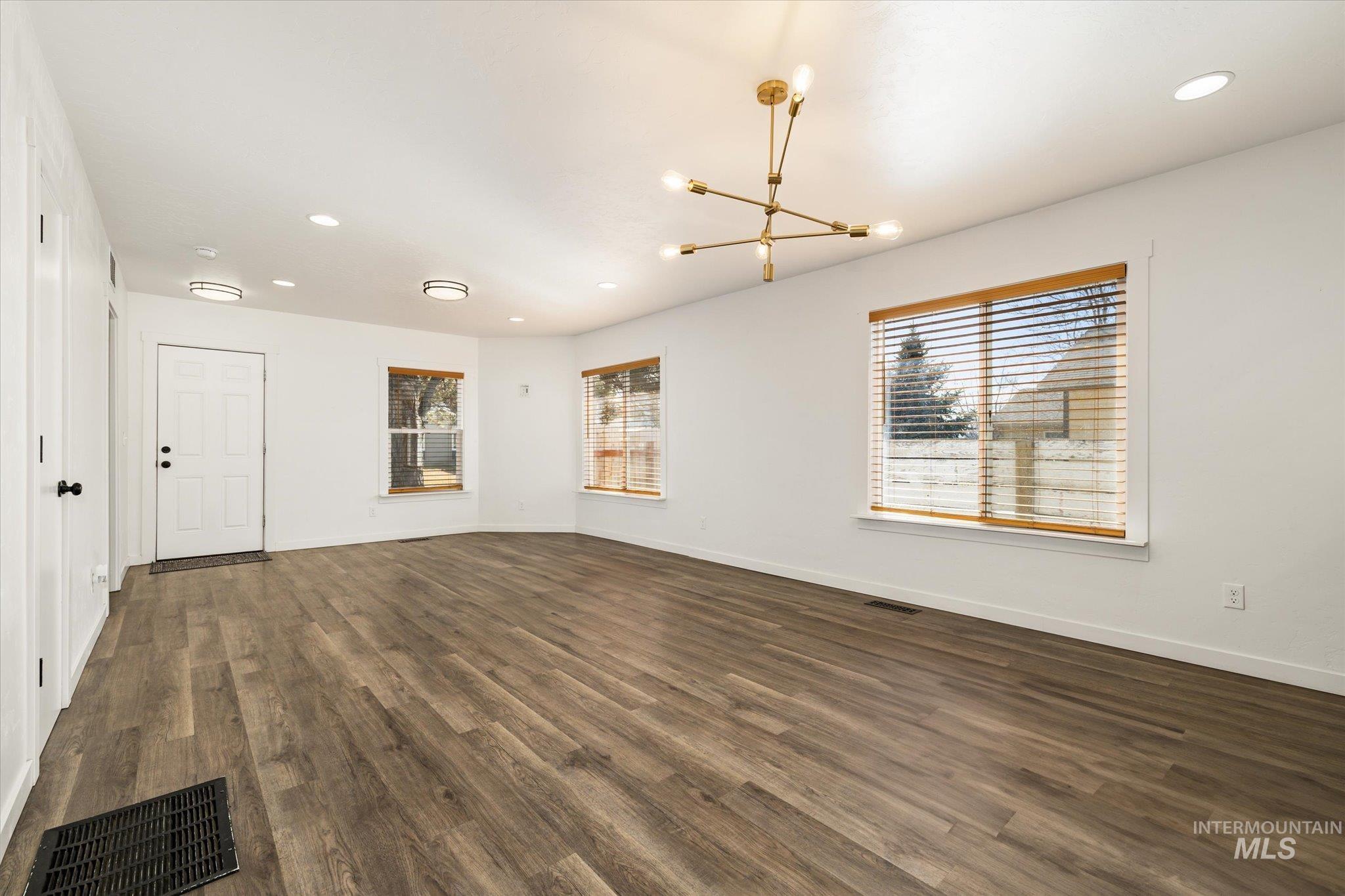 Unfurnished room featuring dark wood-type flooring and hanging lights