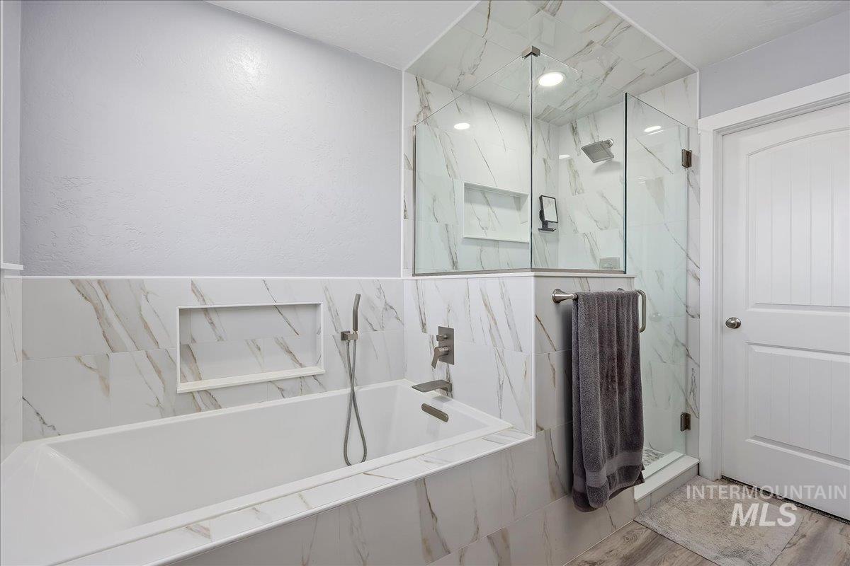 Bathroom featuring a bath and a marble finish shower