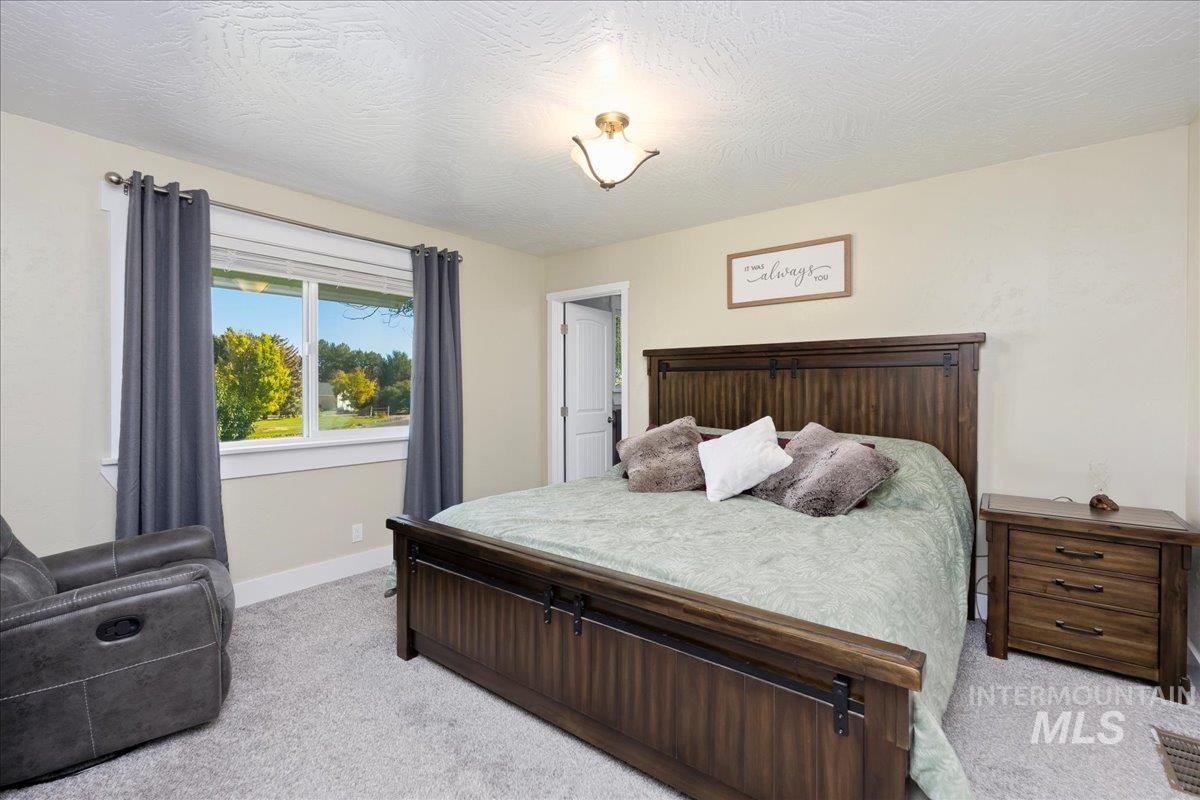 Carpeted bedroom featuring a textured ceiling and baseboards