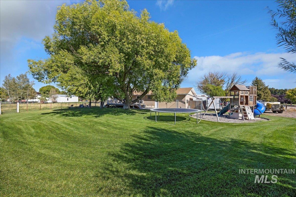 View of yard featuring a trampoline and a playground