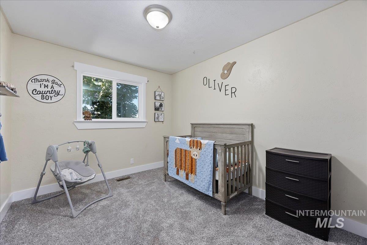 Bedroom with a crib and carpet flooring