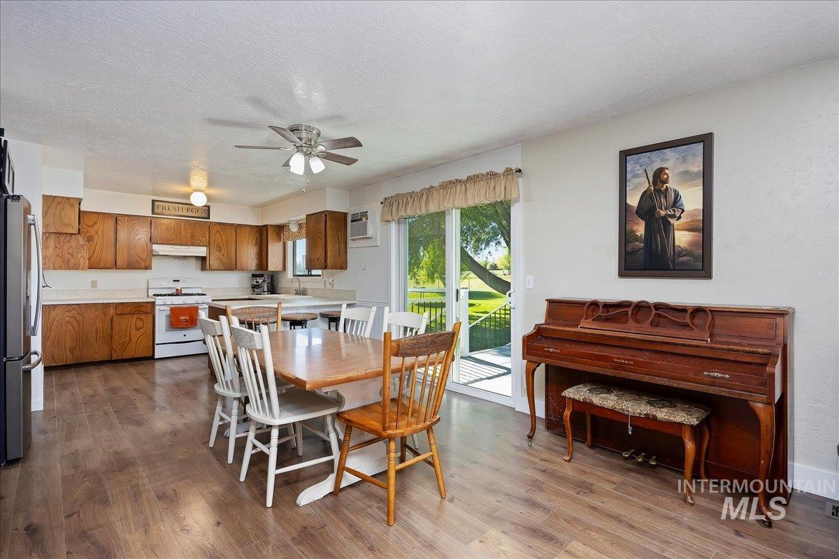 Dining area featuring dark wood-style flooring, a textured ceiling, ceiling fan, and a wall mounted AC
