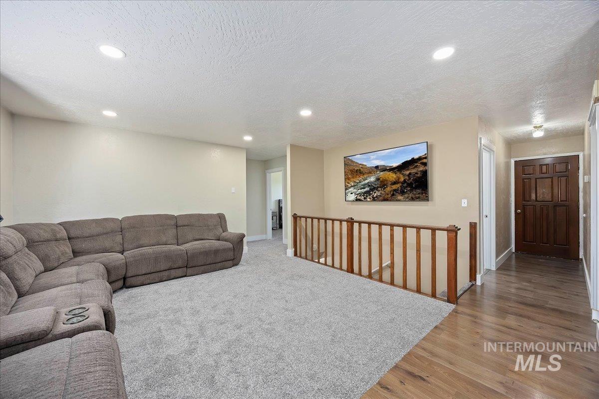 Living area with a textured ceiling, light wood finished floors, and recessed lighting
