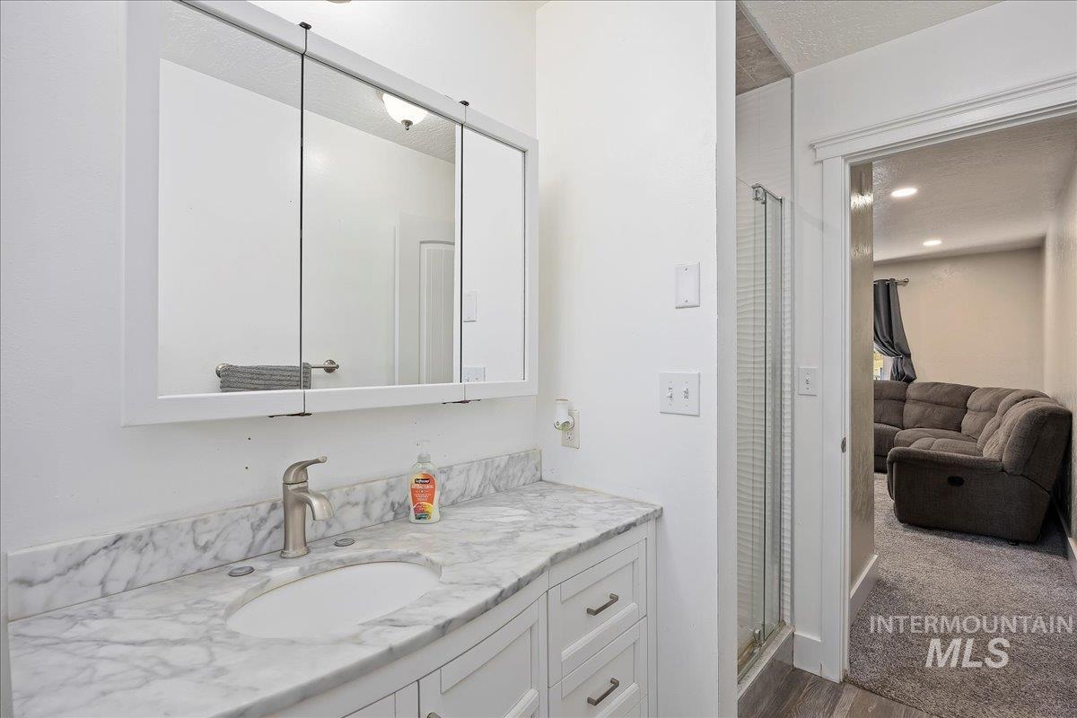 Full bathroom with a stall shower, vanity, ensuite bathroom, dark wood finished floors, and a textured ceiling