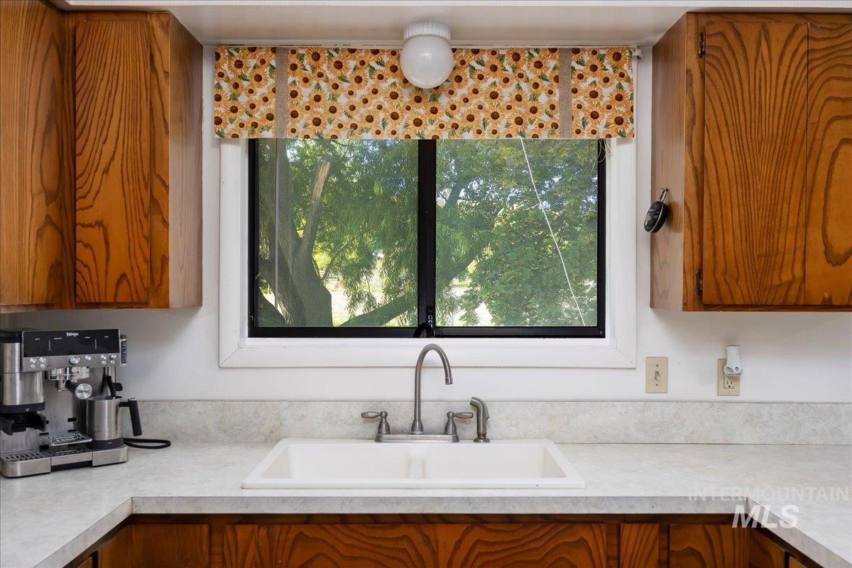 Kitchen featuring brown cabinetry, light countertops, and plenty of natural light