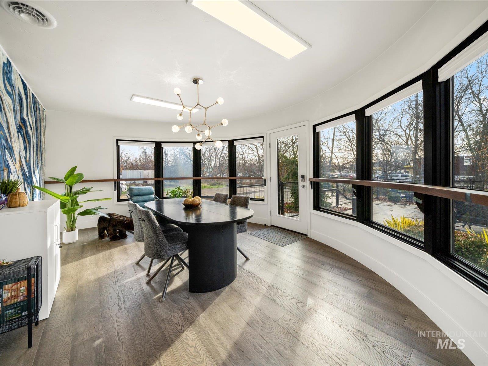 Dining room featuring light wood-style floors, a chandelier, and healthy amount of natural light