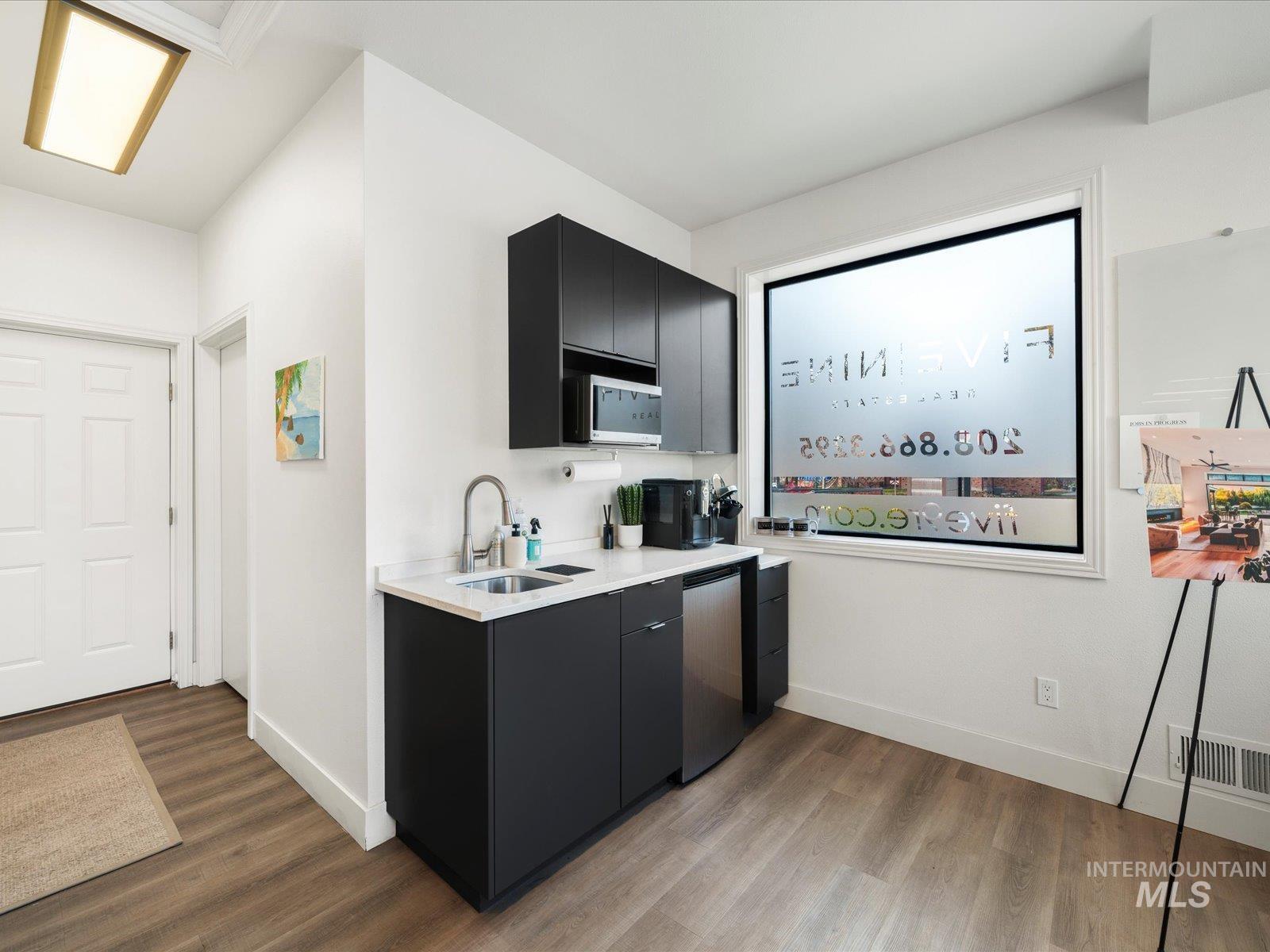 Kitchen with dark cabinetry, light wood-type flooring, modern cabinets, and stainless steel microwave